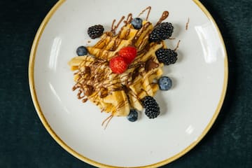 a plate of food with berries and chocolate drizzle