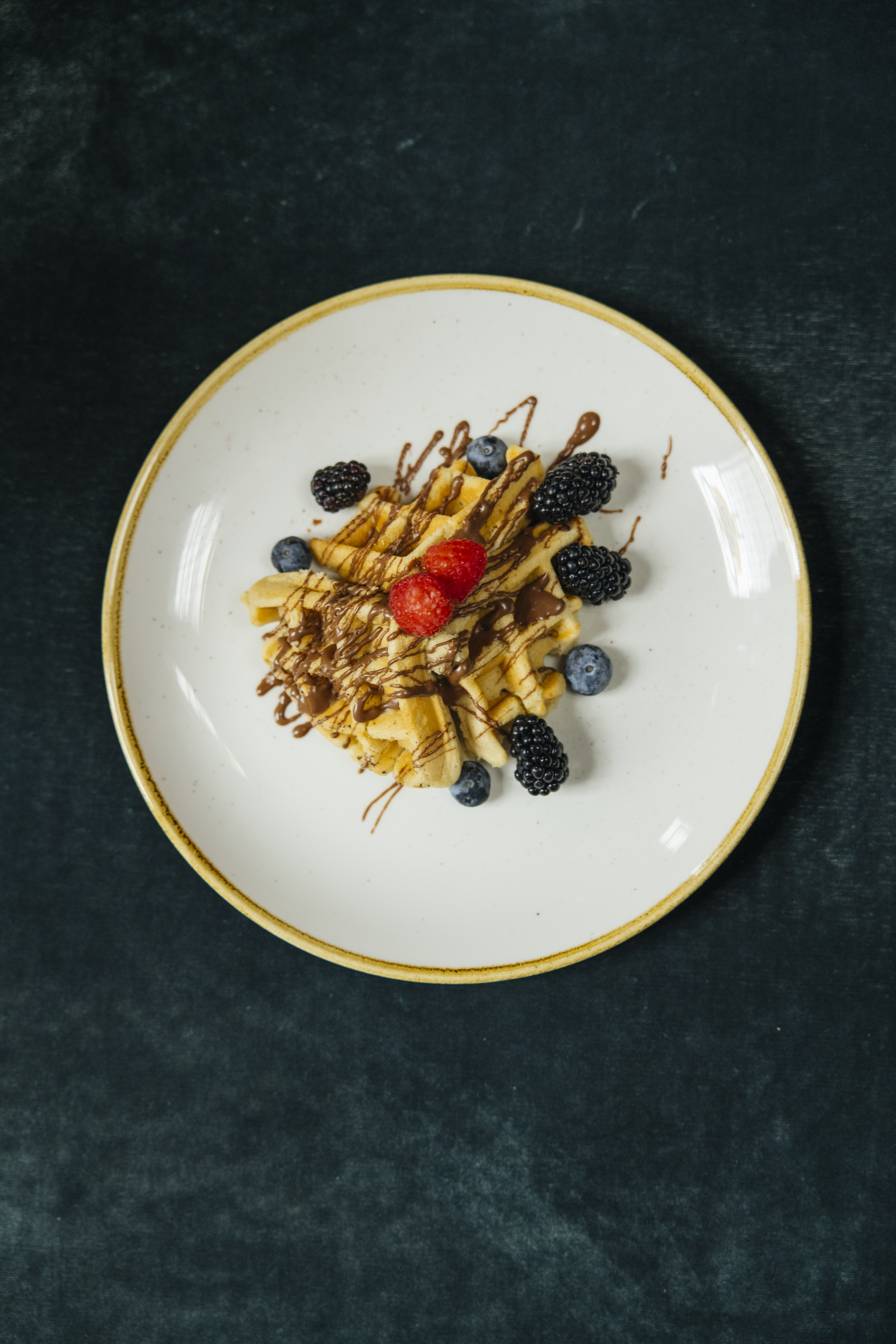 a plate of food with berries and chocolate drizzle