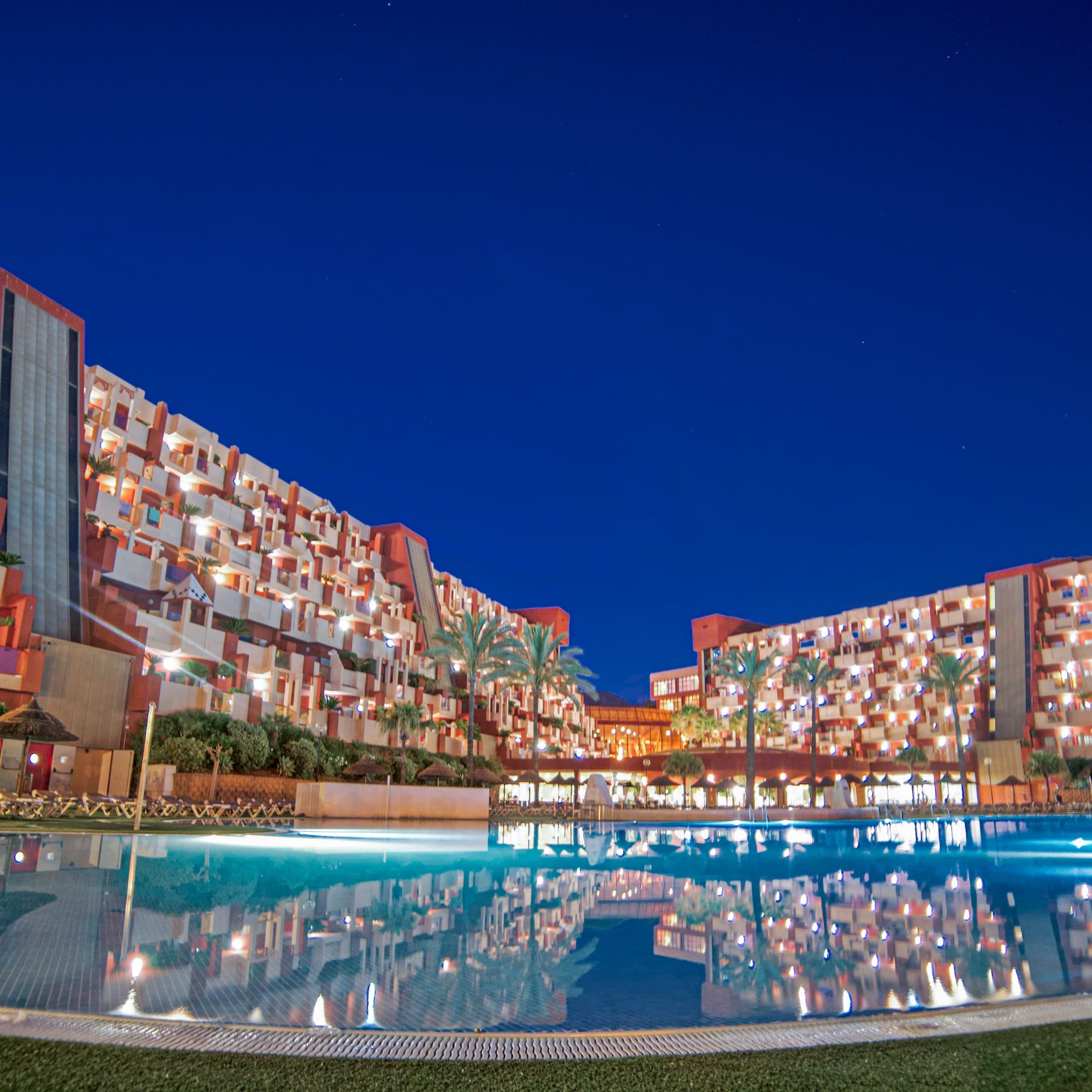 a pool with lights on the building