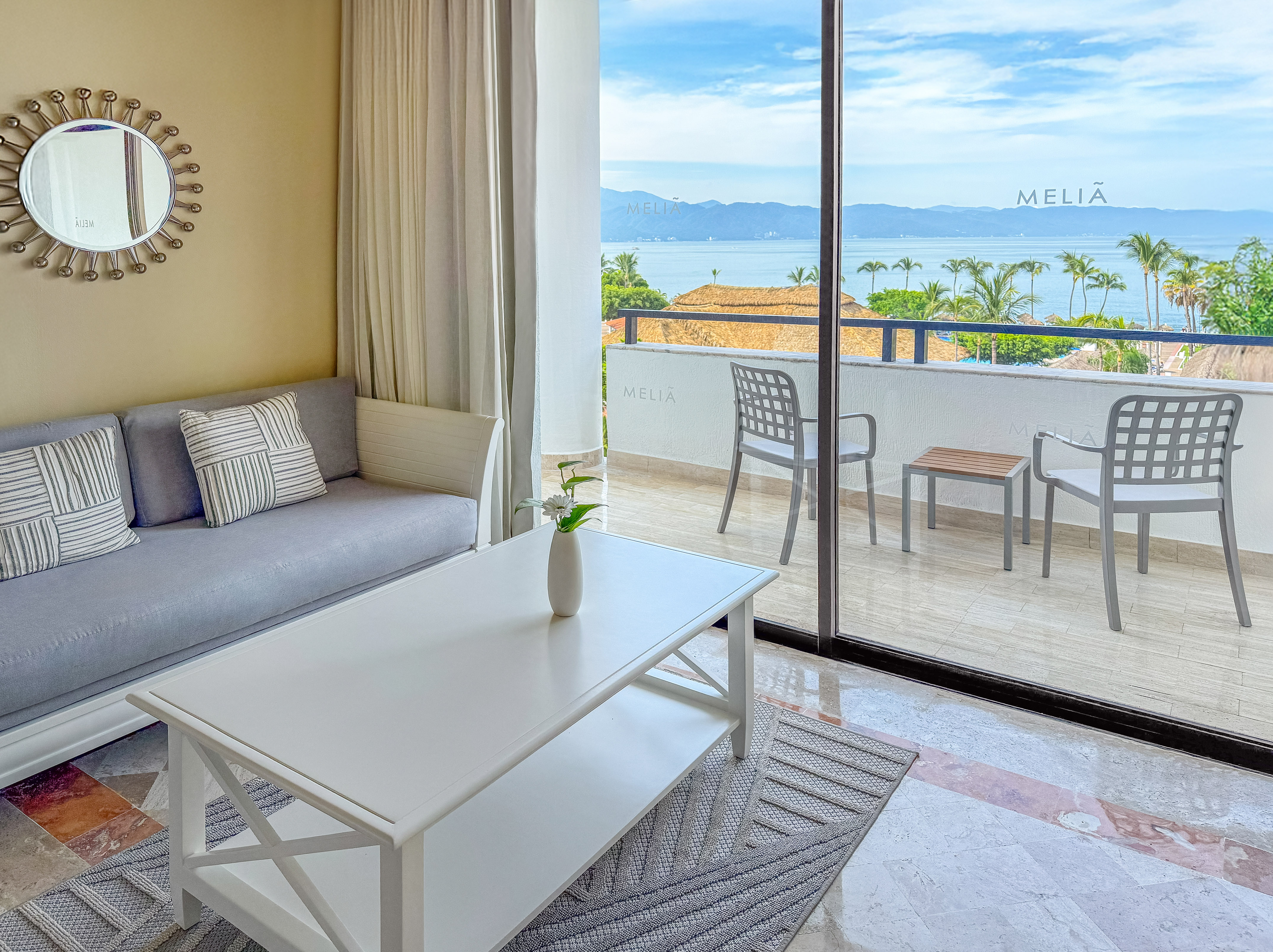 Melia hotel suite living room with ocean view balcony, sofa, and palm trees.
