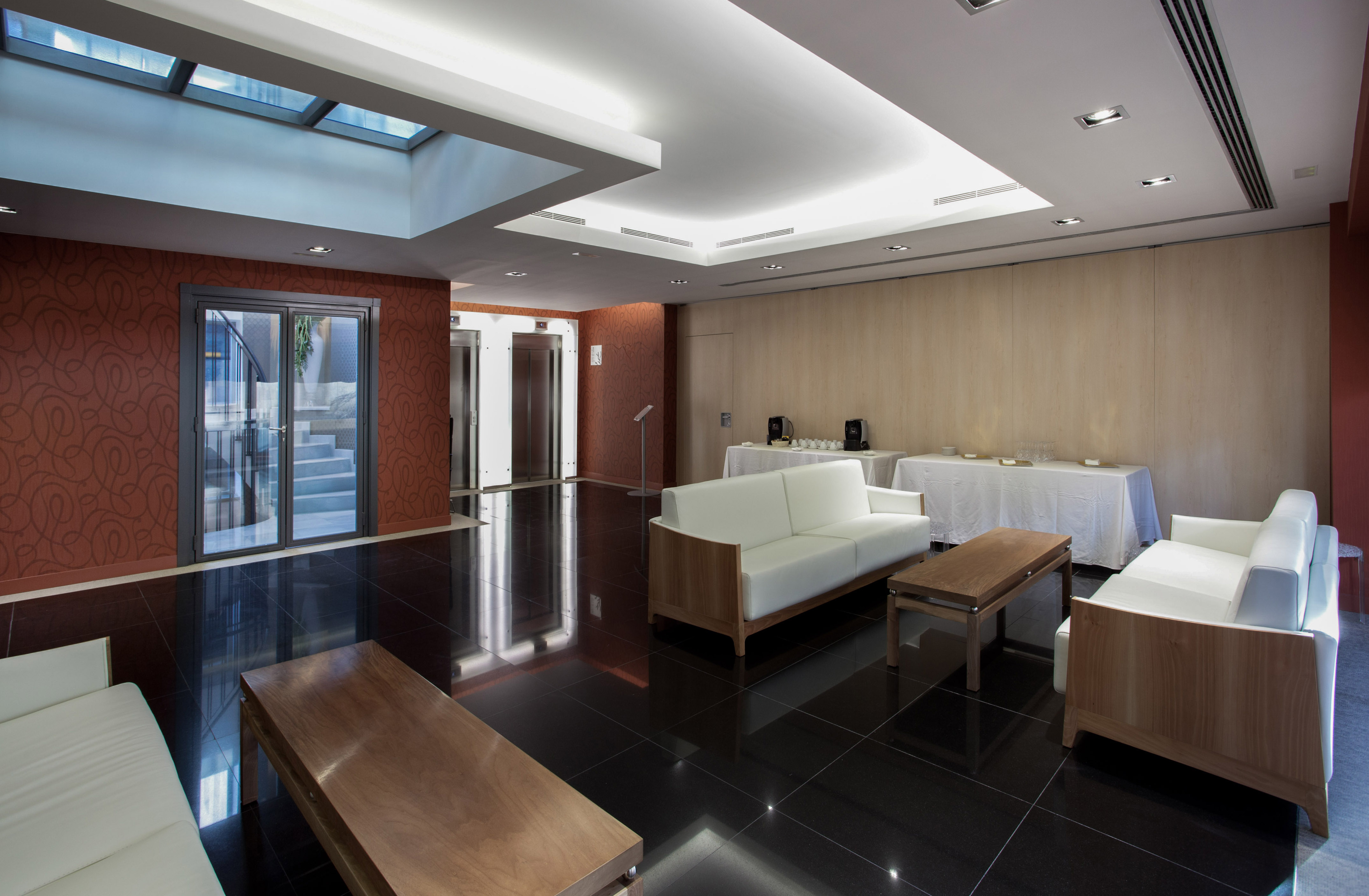 Modern hotel lobby with white sofas, black tile floor, and elevators.
