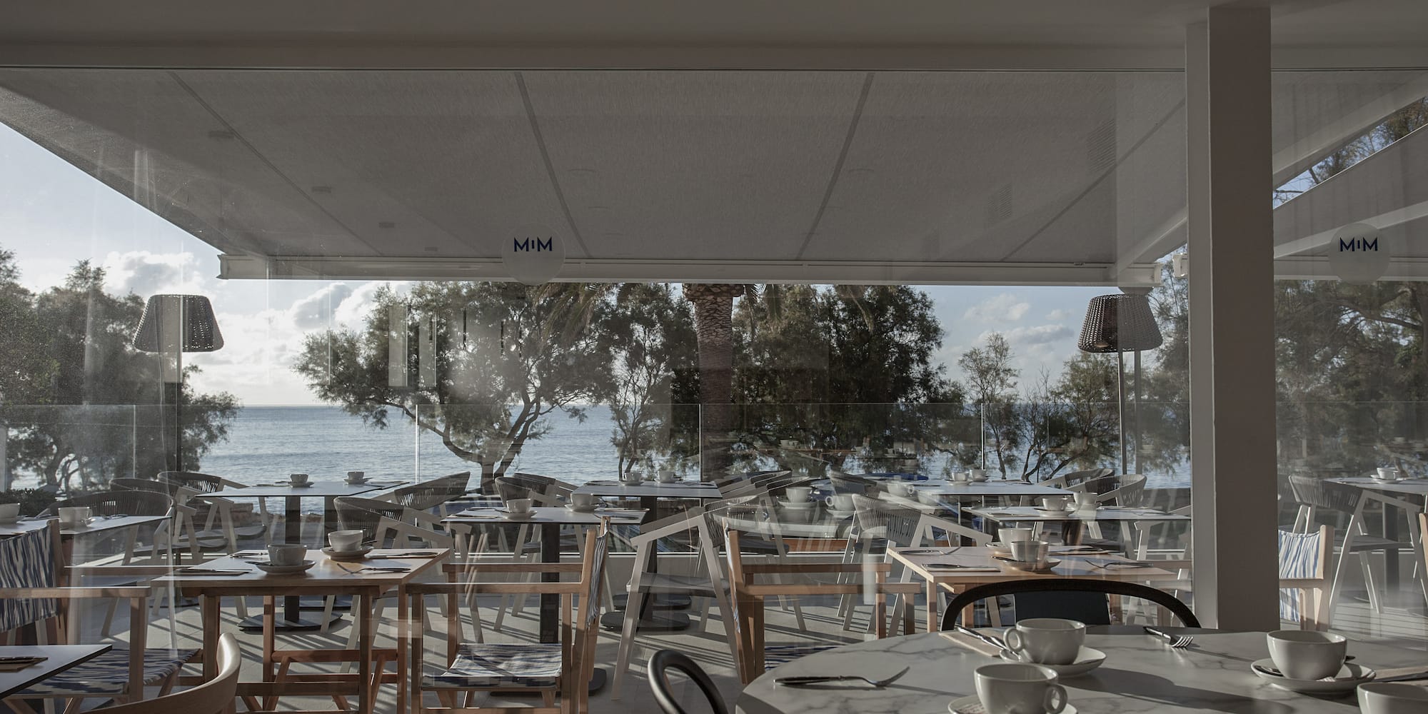a room with tables and chairs and a view of the ocean