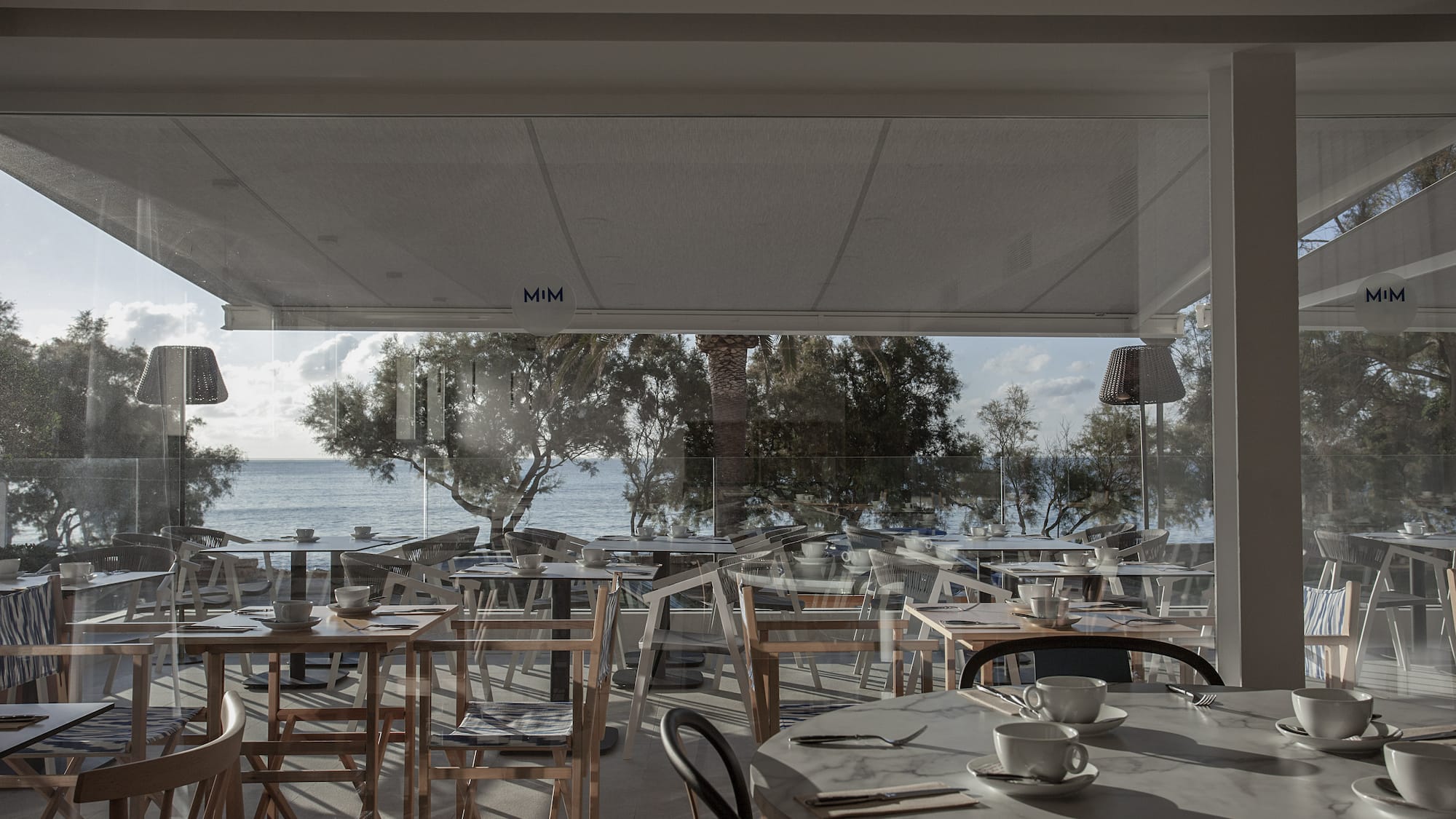 a room with tables and chairs and a view of the ocean