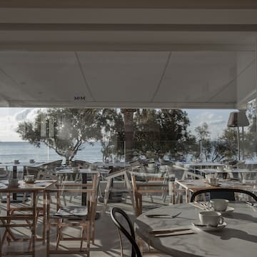 a room with tables and chairs and a view of the ocean