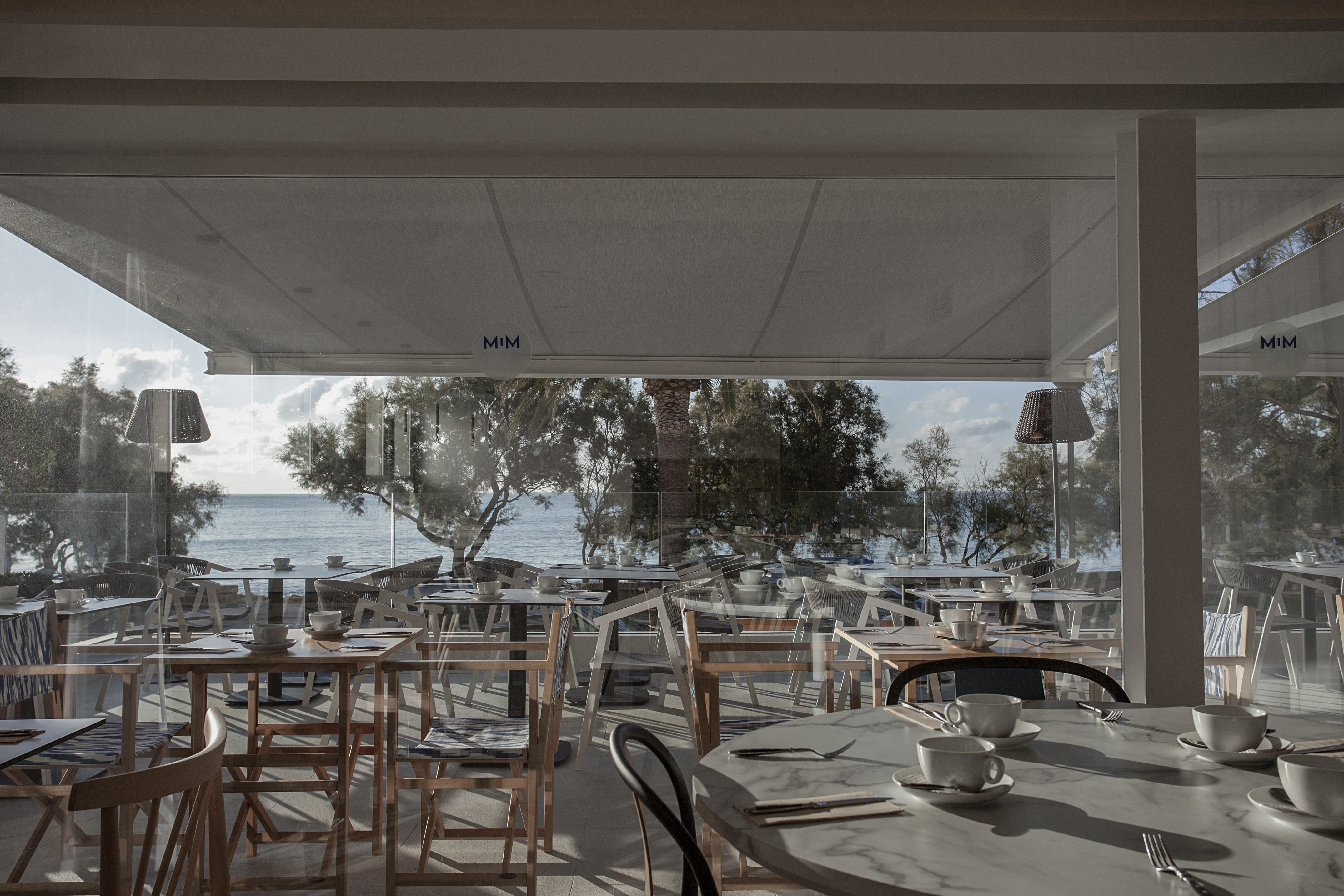 a room with tables and chairs and a view of the ocean
