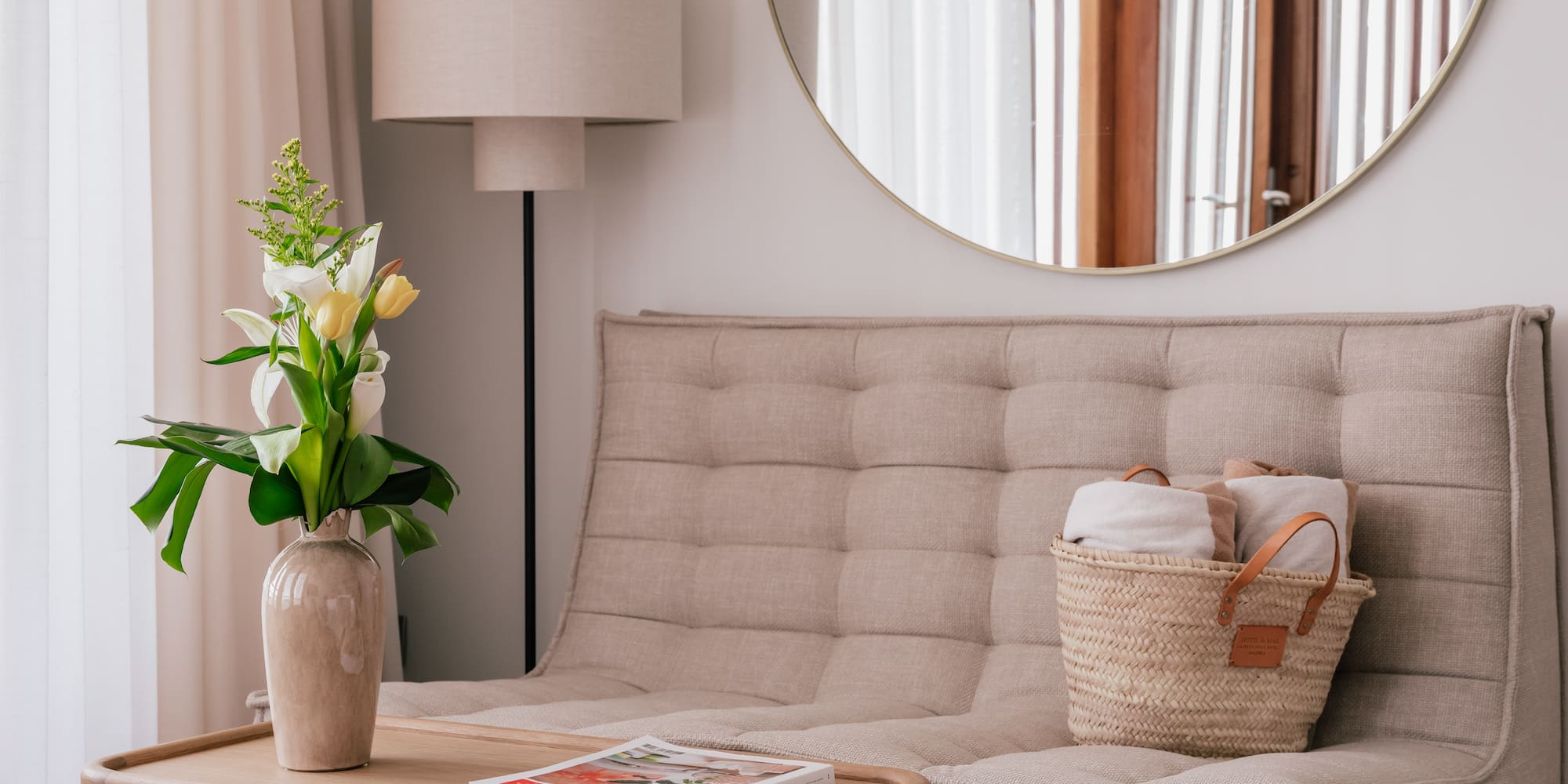 a couch with a basket of towels and a vase of flowers