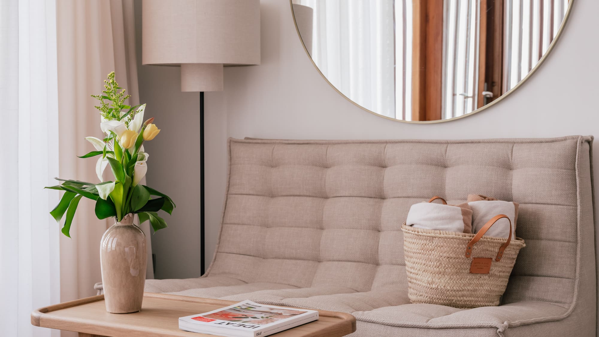 a couch with a basket of towels and a vase of flowers