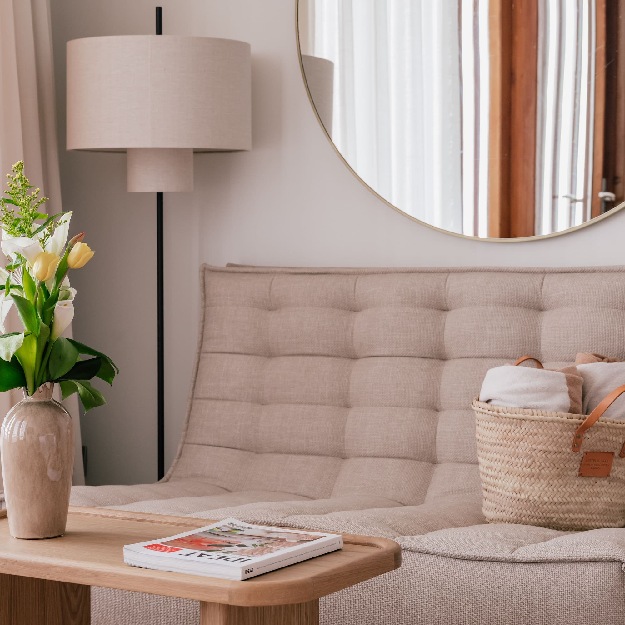 a couch with a basket of towels and a vase of flowers