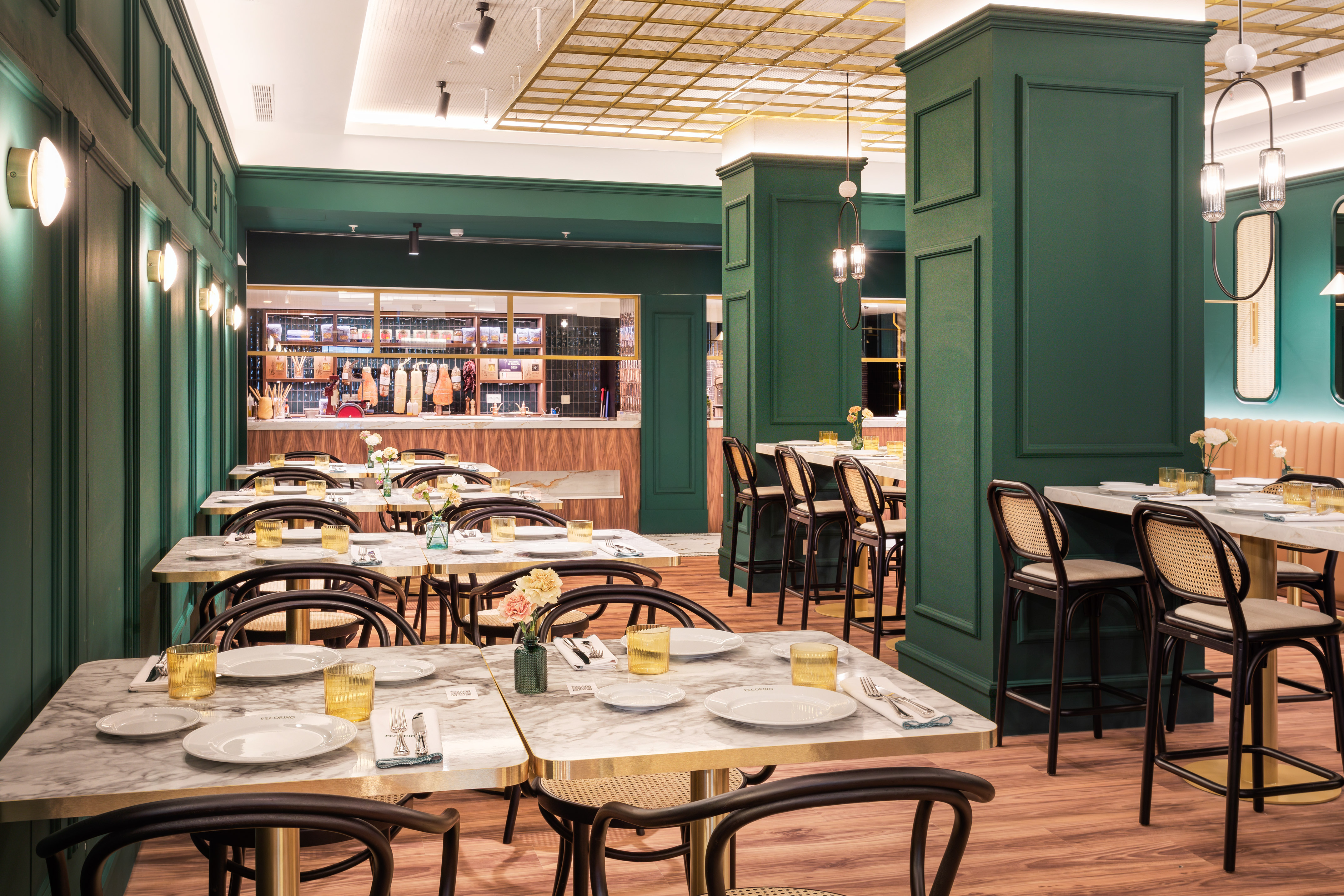 Restaurant dining with green walls, marble tables, cane chairs, and a deli counter.