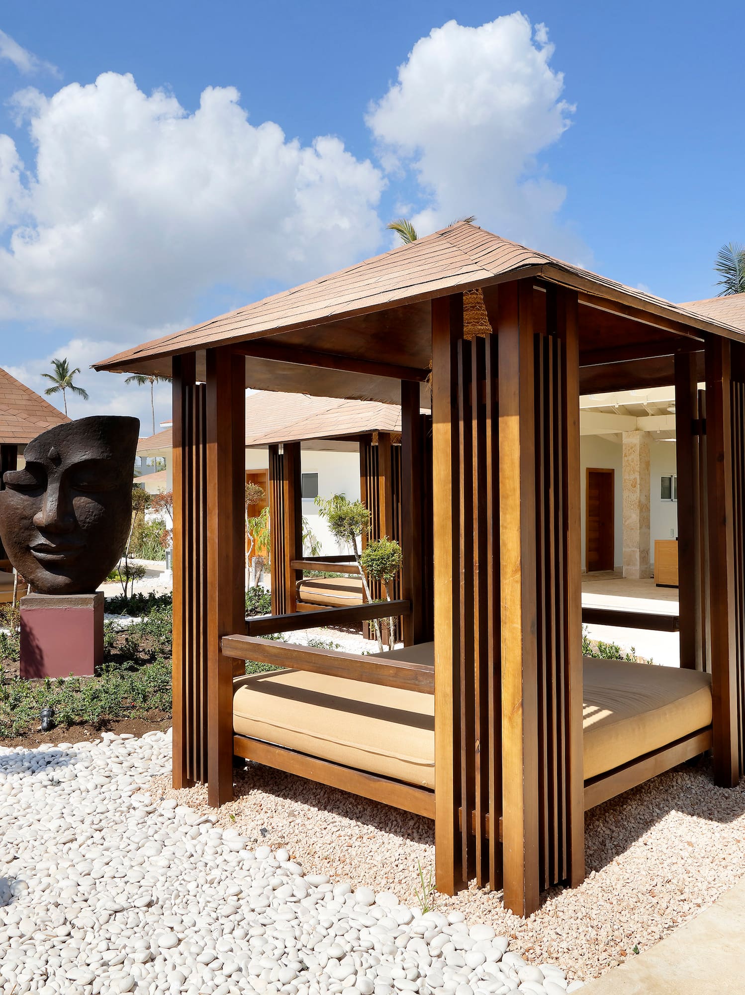 a wooden gazebo with a large head statue in the background