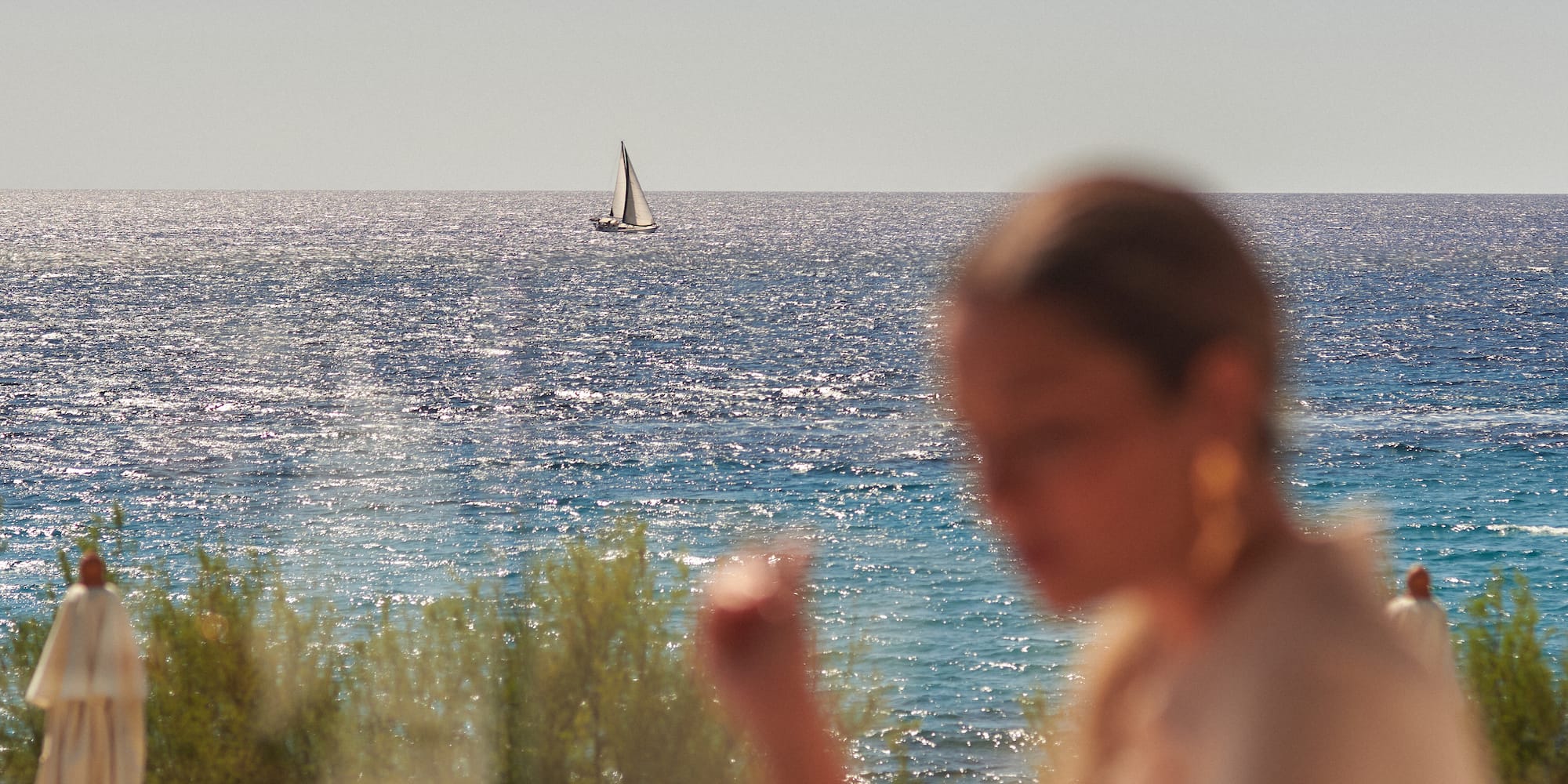 a woman sitting at a table with a sailboat in the background