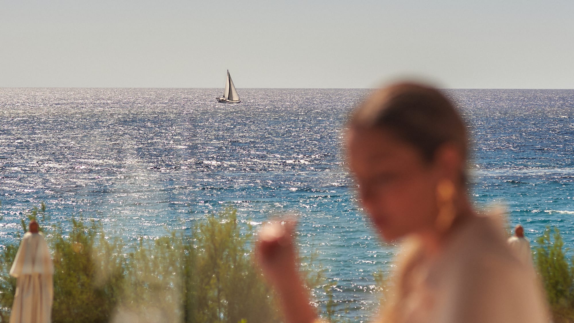 a woman sitting at a table with a sailboat in the background