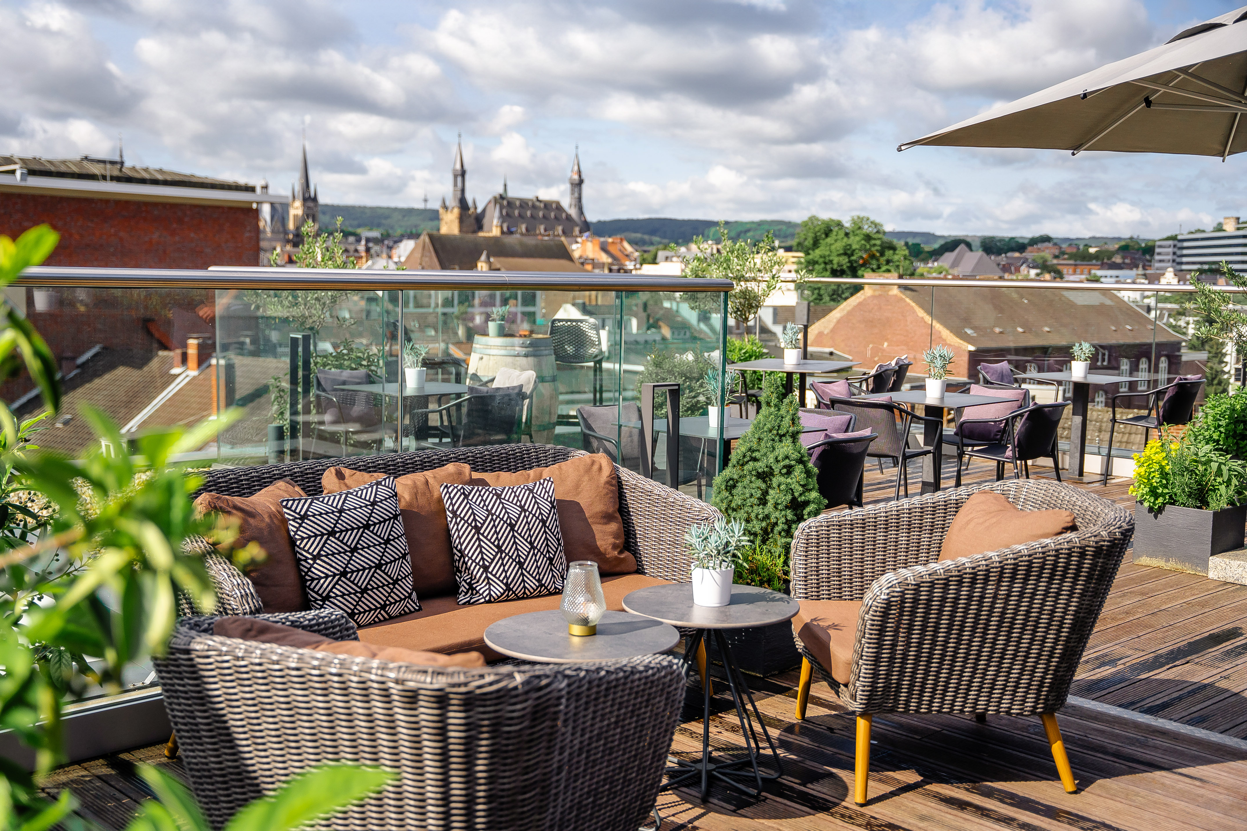 Rooftop terrace lounge with wicker furniture and historic city view.