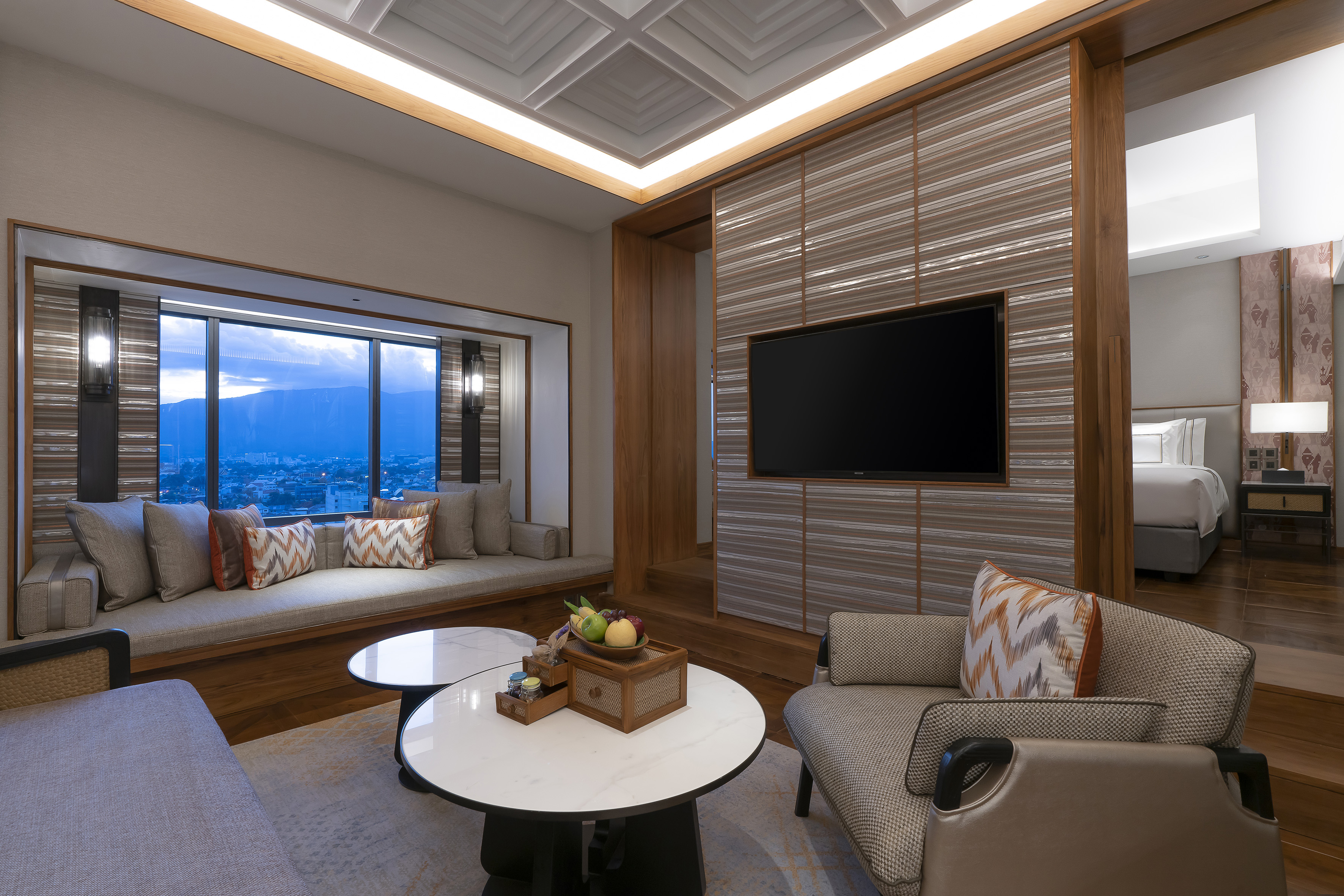 Luxury hotel suite living room with city view and connecting bedroom.