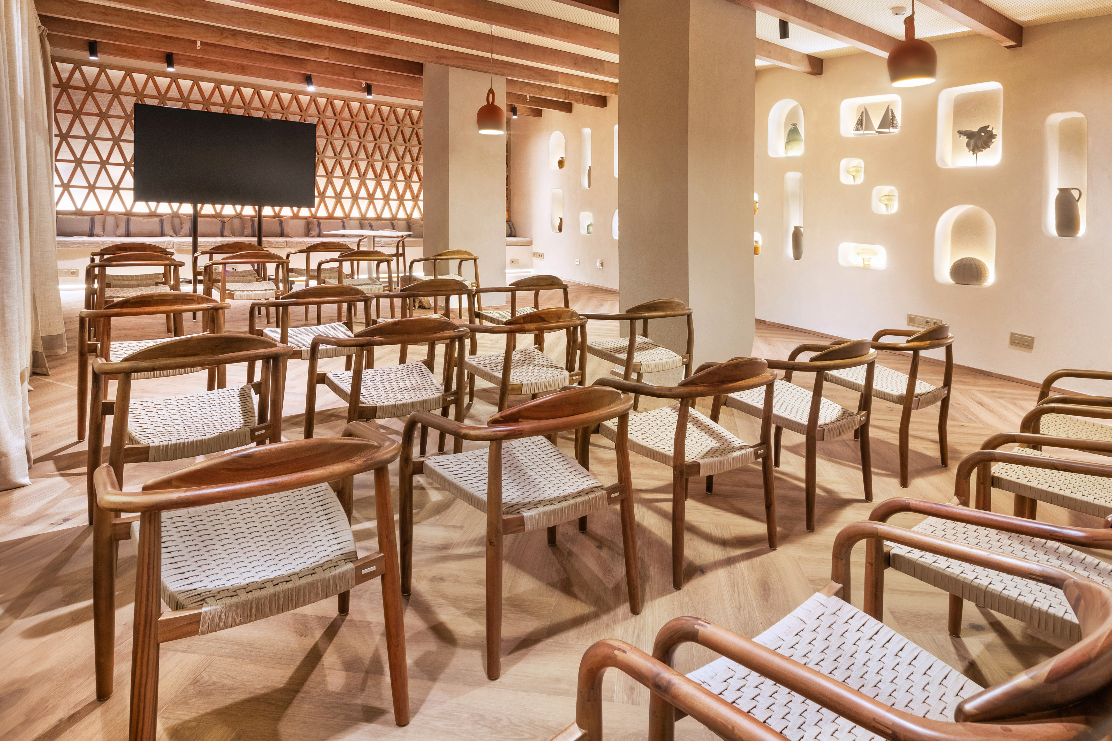 Modern meeting room with wooden chairs, woven seats, and large projection screen.
