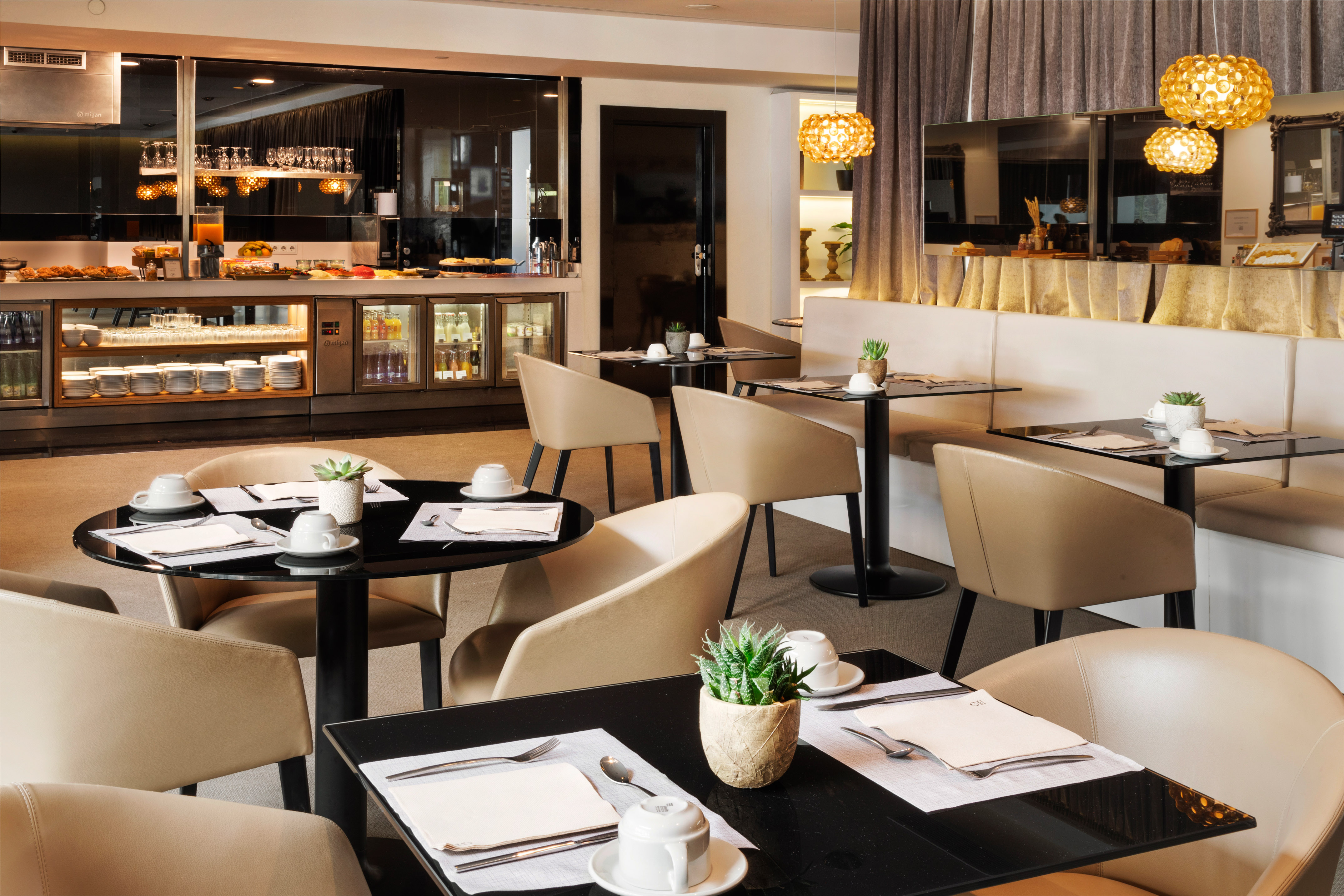 Modern hotel breakfast buffet and dining area with set tables.