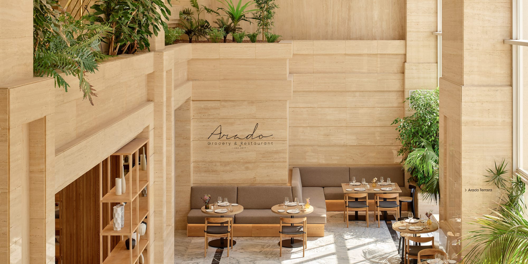 Interior luminoso de restaurante Arado con travertino, plantas y mesas.