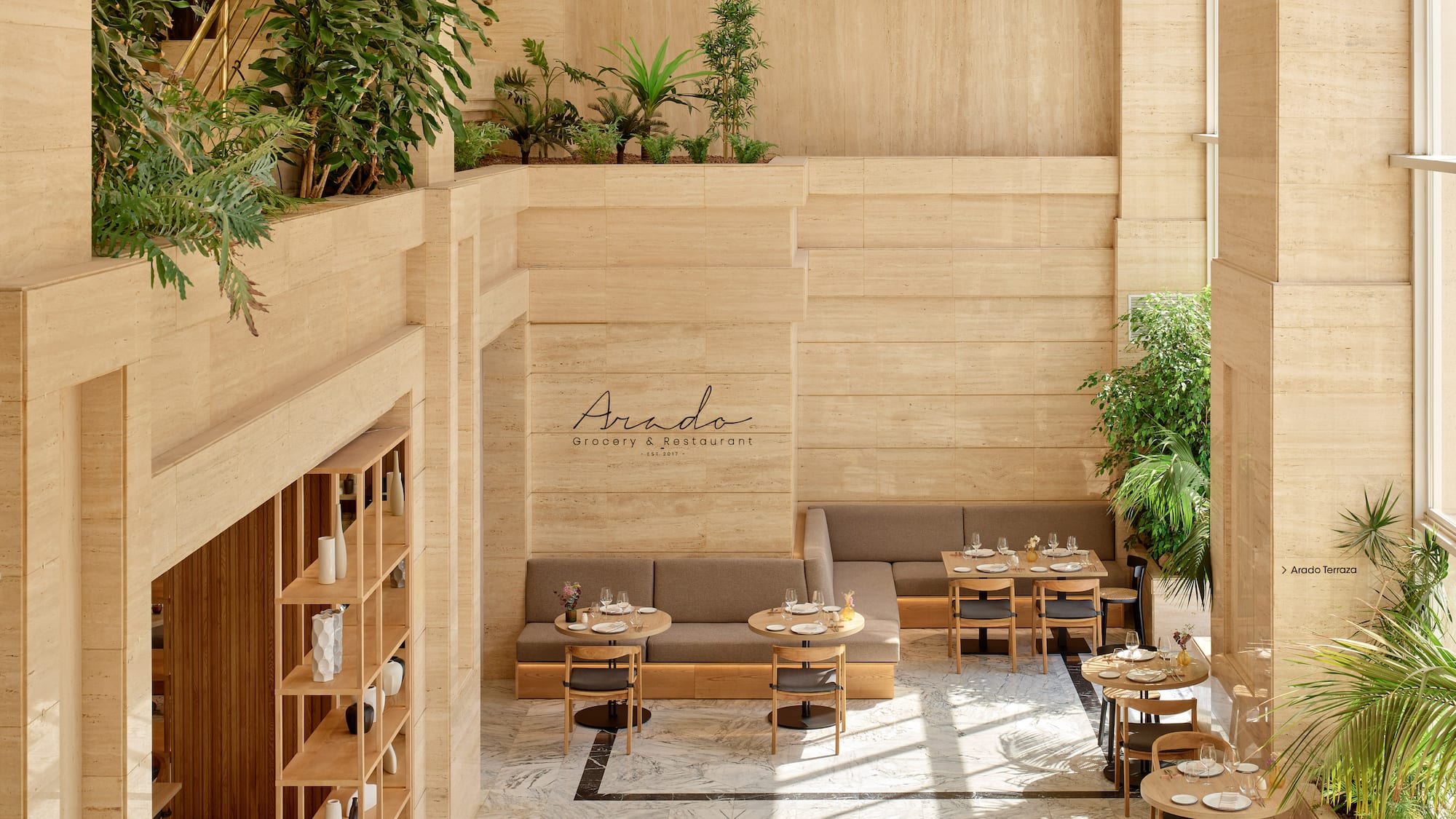 Interior luminoso de restaurante Arado con travertino, plantas y mesas.