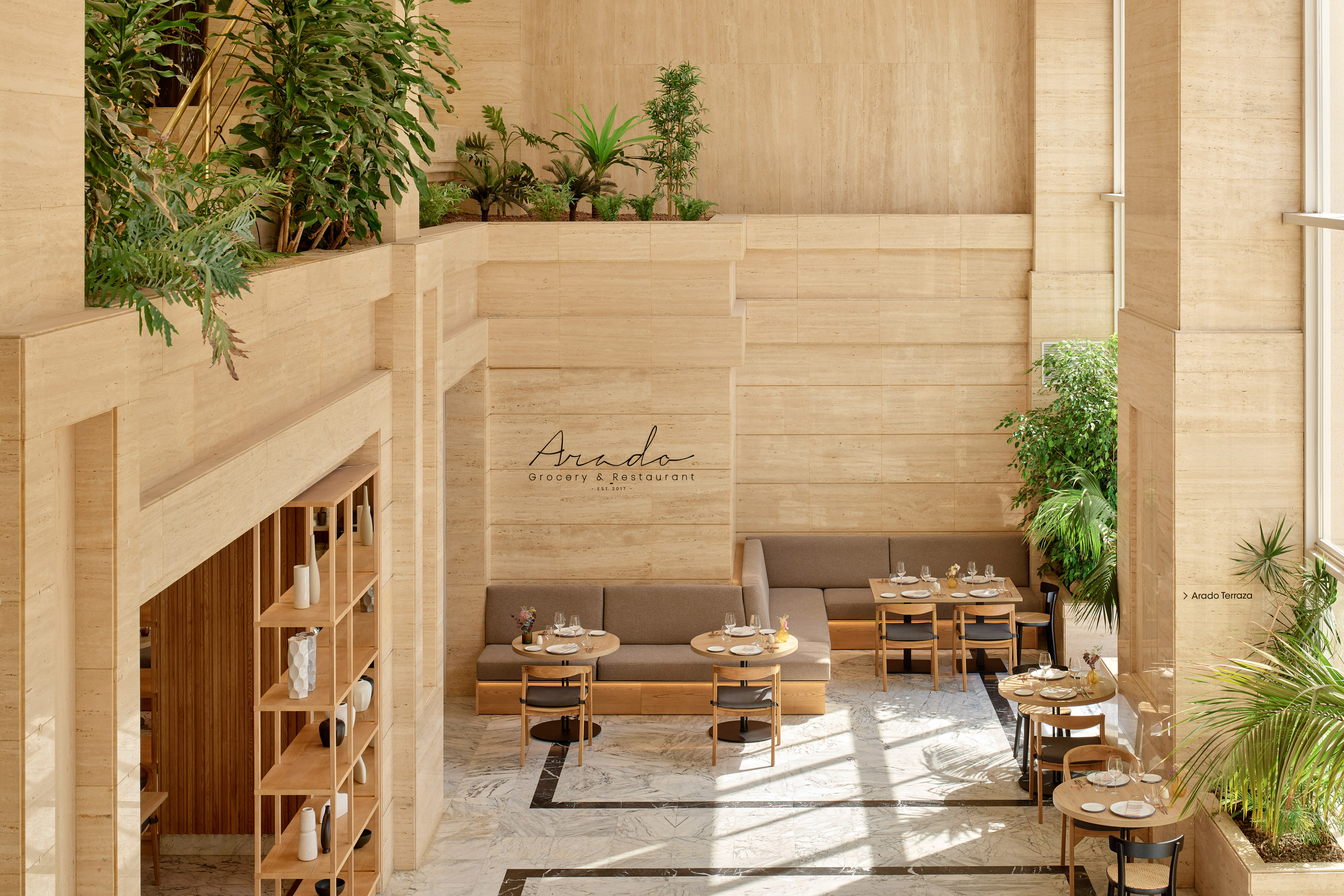 Interior luminoso de restaurante Arado con travertino, plantas y mesas.