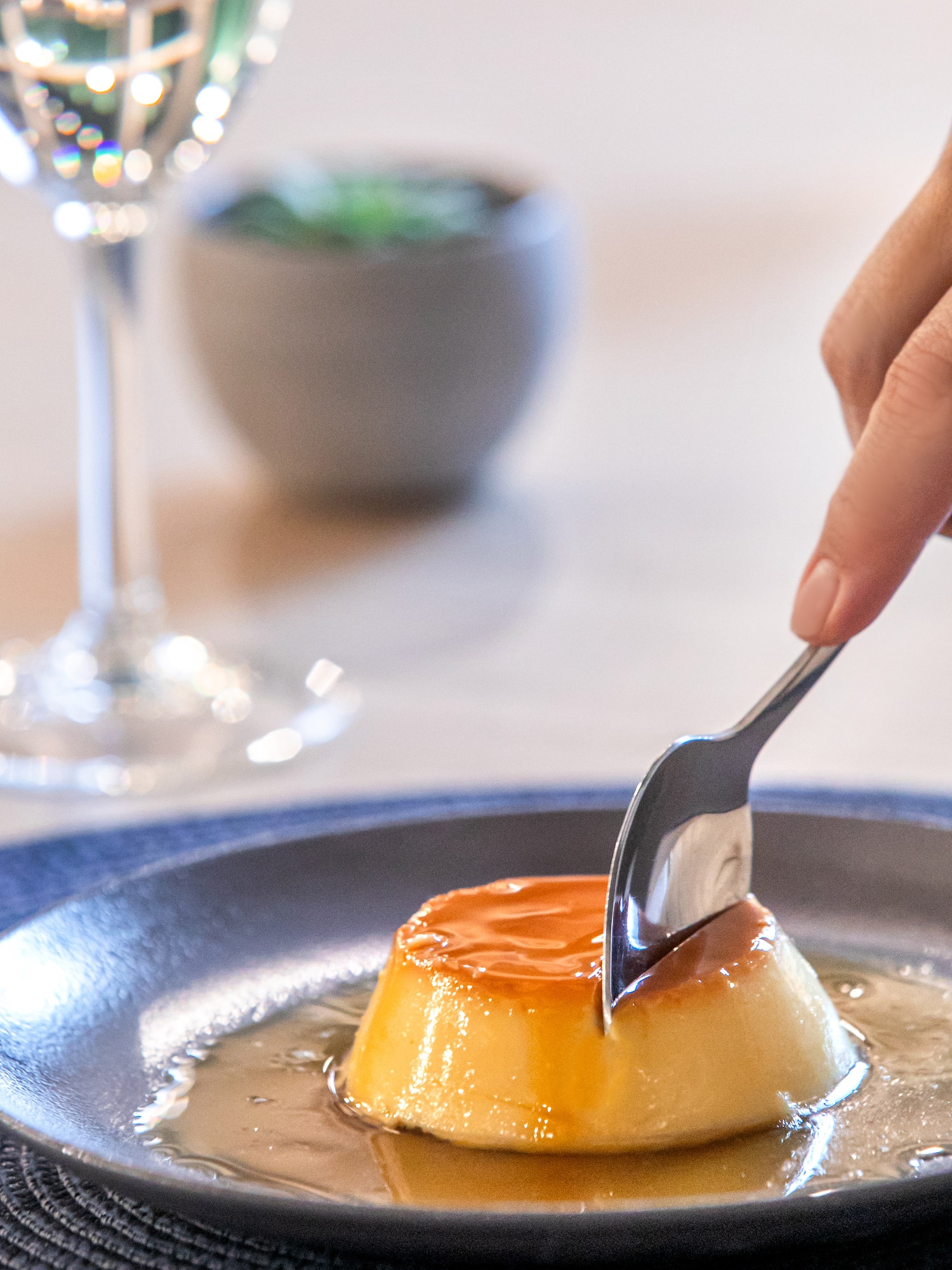 a hand holding a spoon over a flan