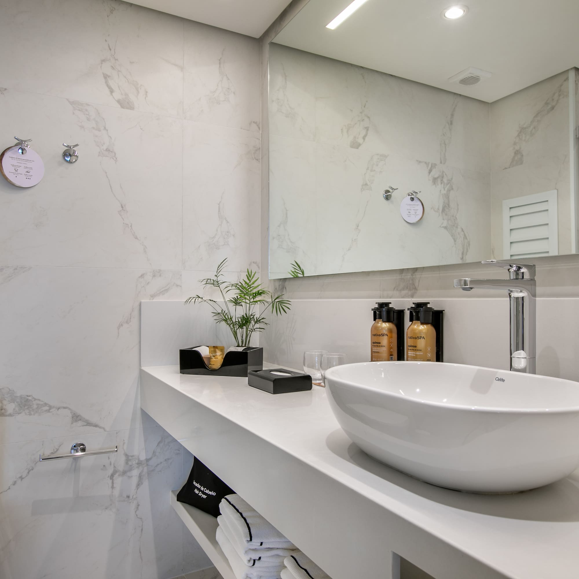 Modern white marble bathroom with vanity, oval sink, and large mirror.