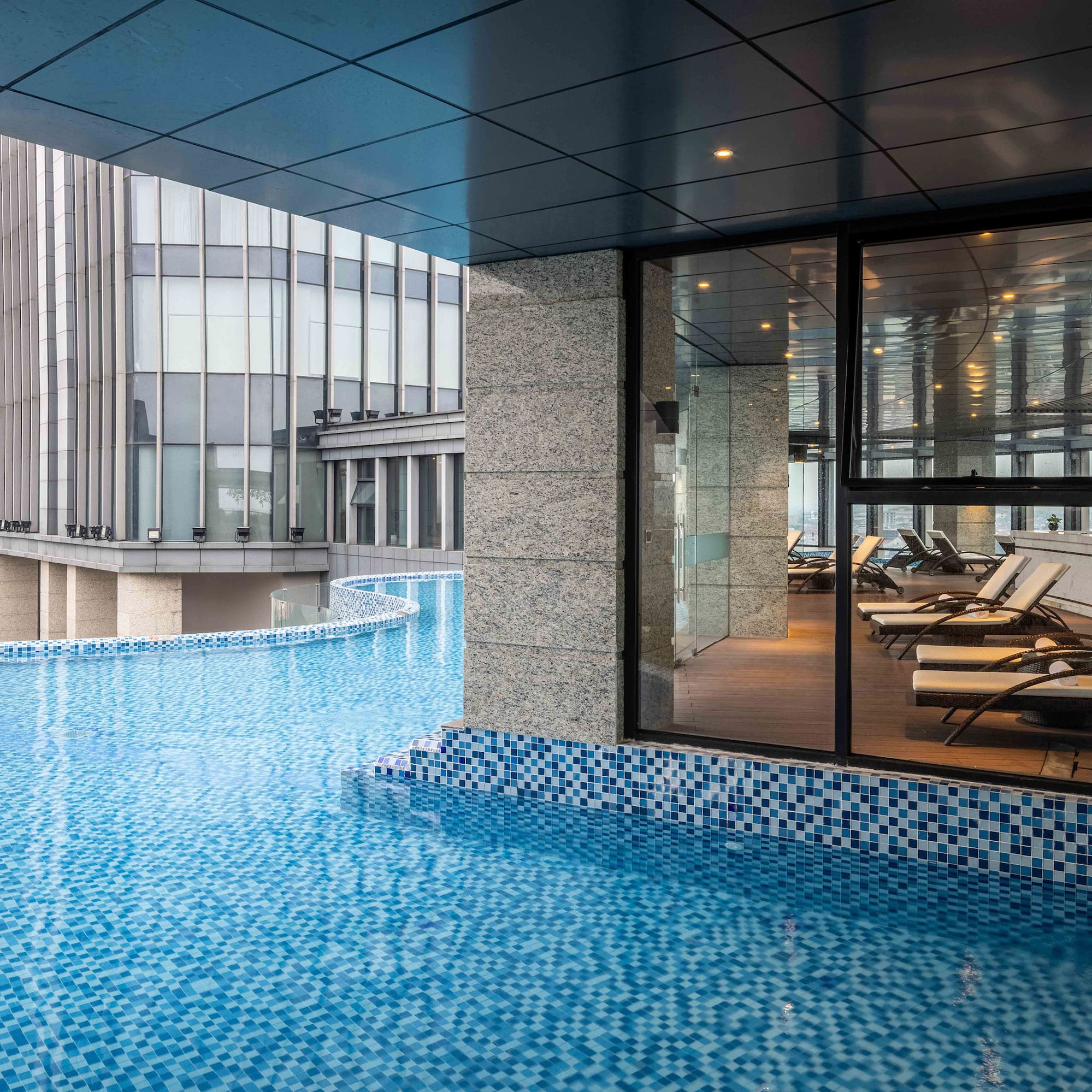a pool with a glass wall and a building