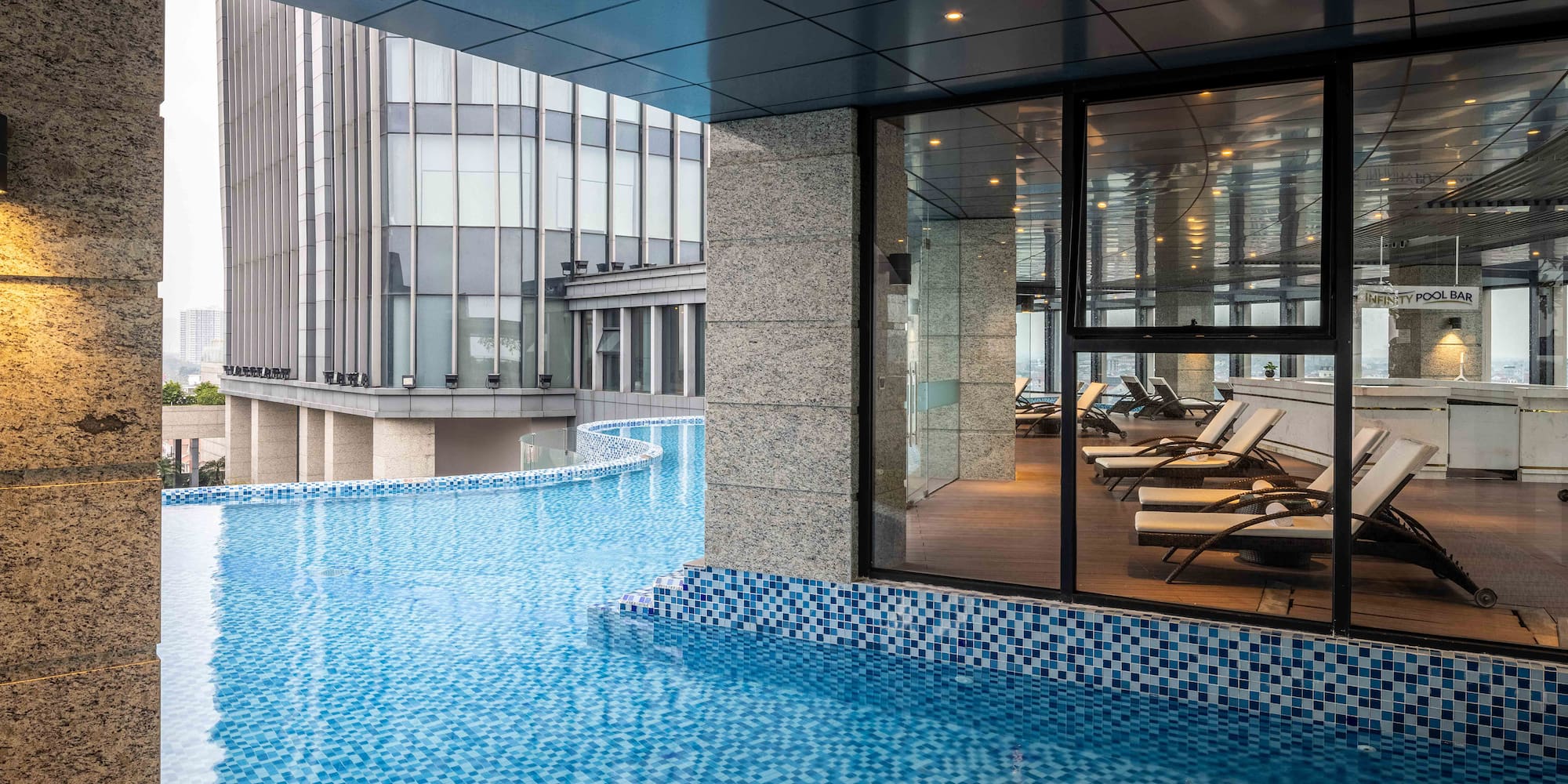 a pool with a glass wall and a building