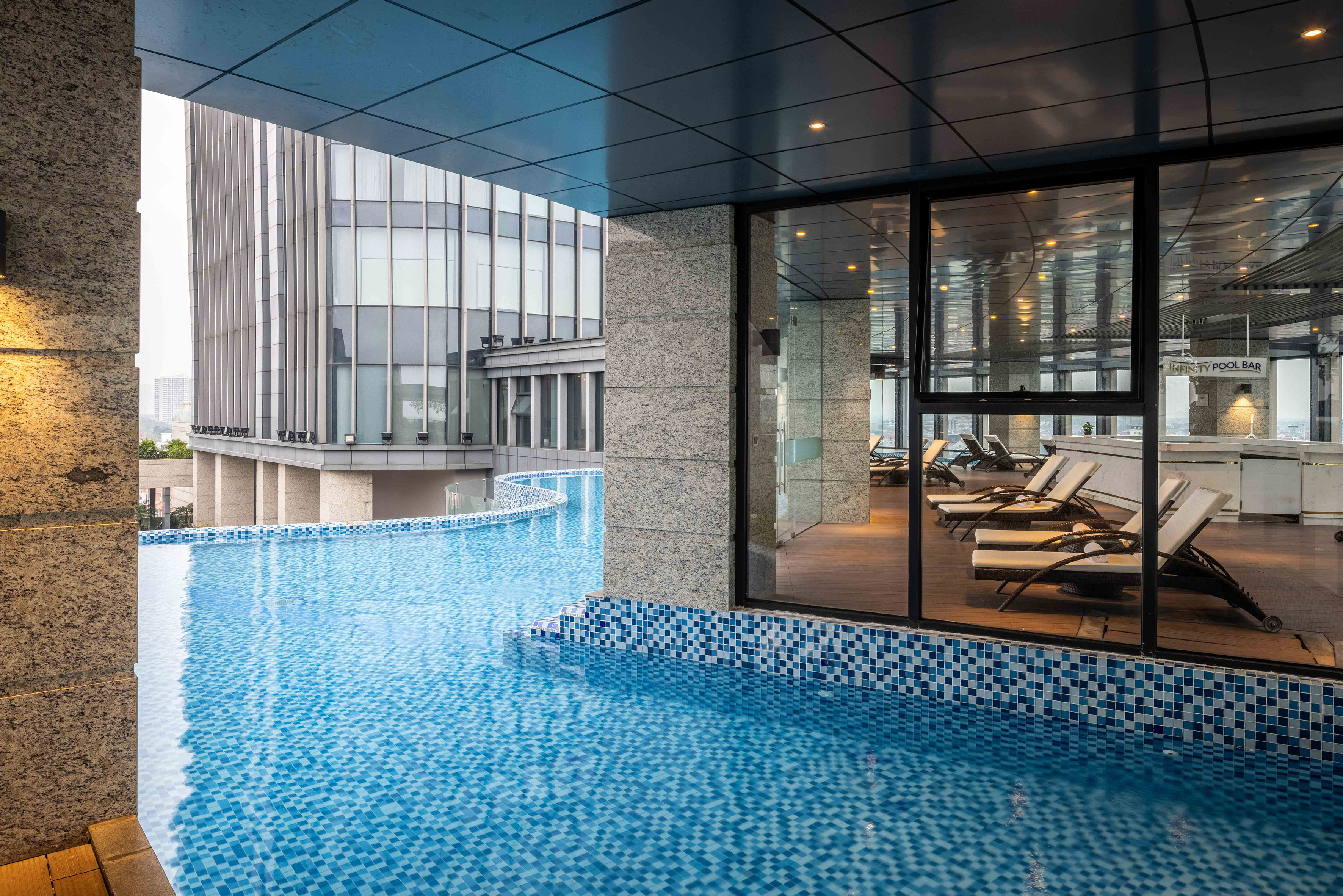 a pool with a glass wall and a building