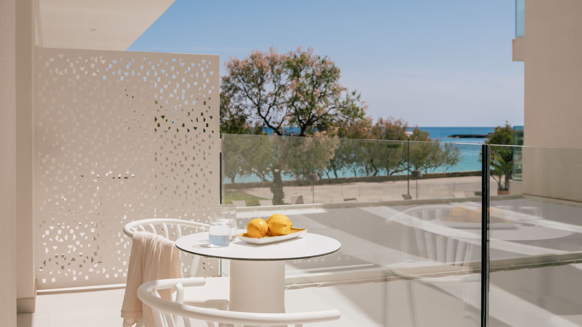 White hotel balcony with lemons, water, and clear blue sea view.