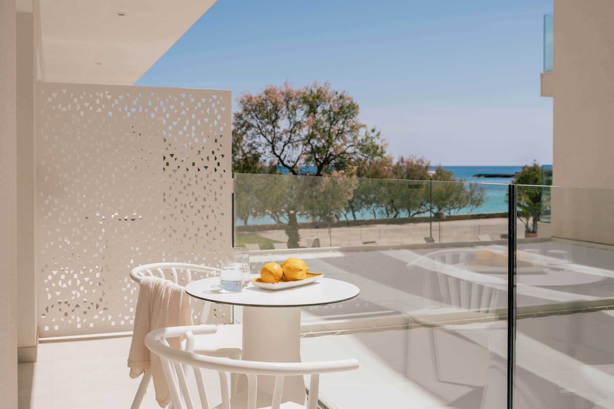 White hotel balcony with lemons, water, and clear blue sea view.