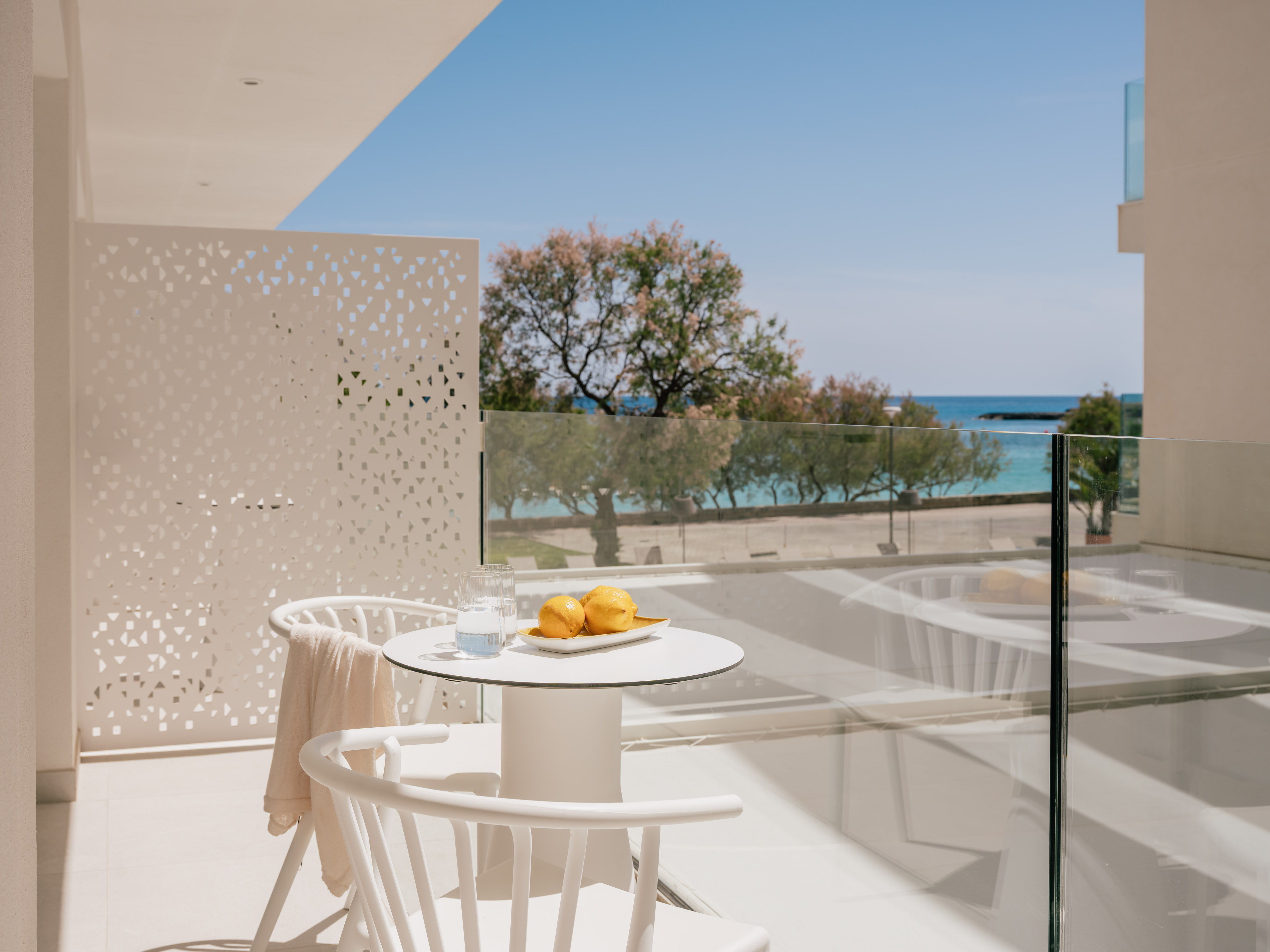 White hotel balcony with lemons, water, and clear blue sea view.