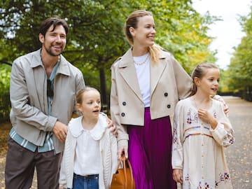 a man and woman with two children walking in a park