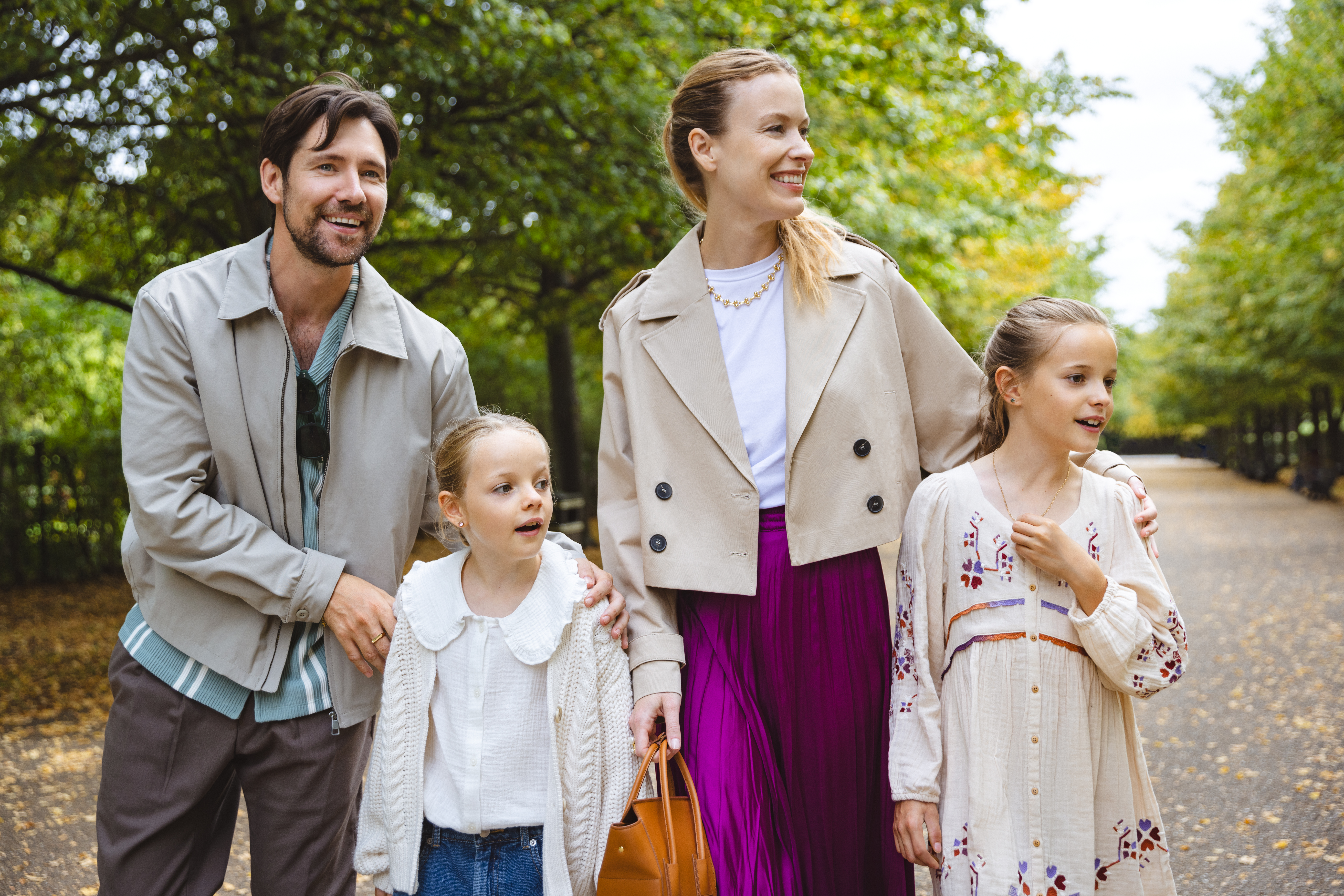 Family of four, parents and two girls, walking happily in an autumn park.