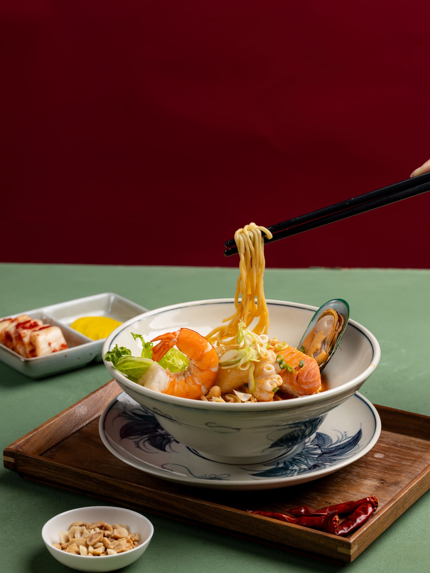 a person holding chopsticks over a bowl of noodles