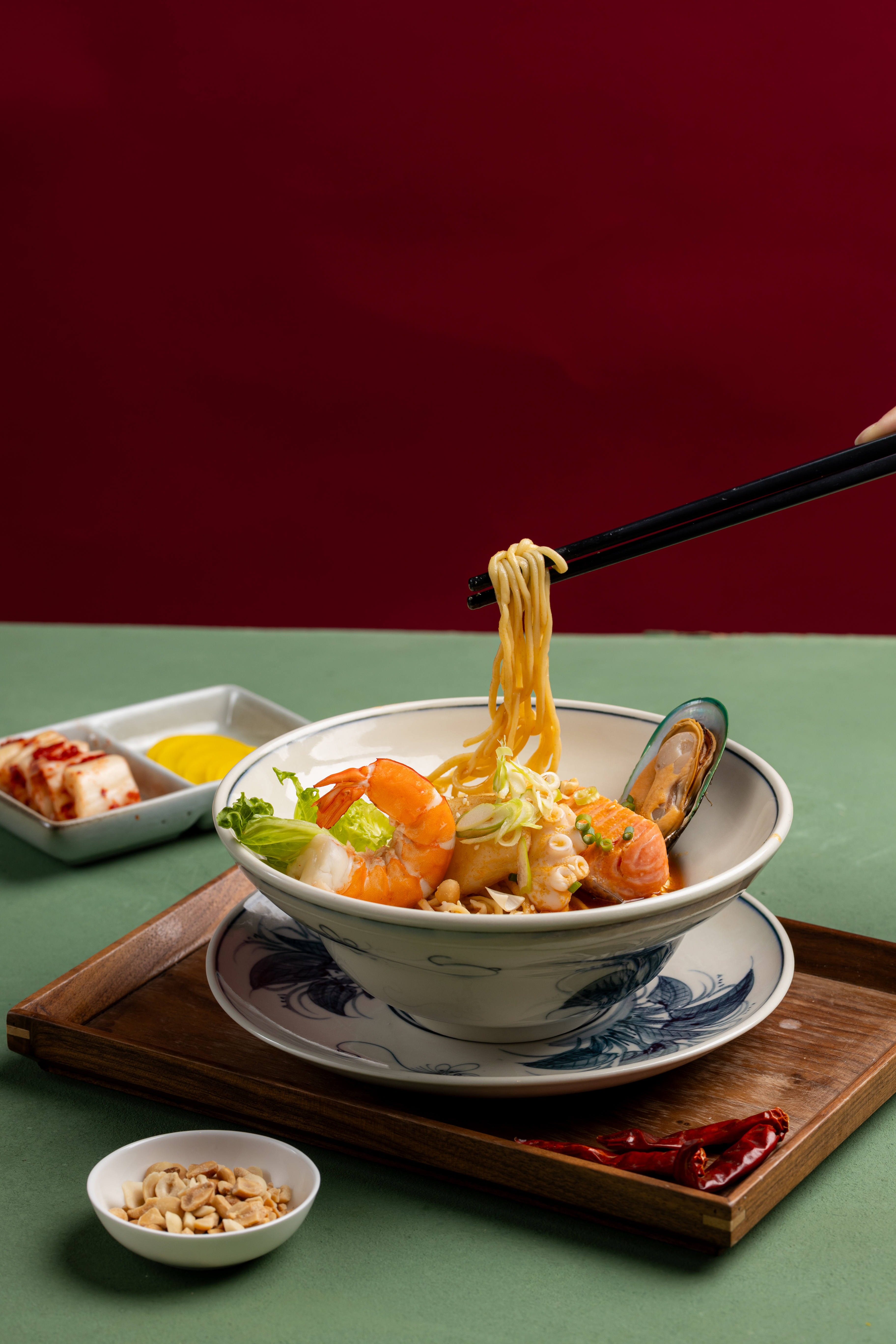 a person holding chopsticks over a bowl of noodles