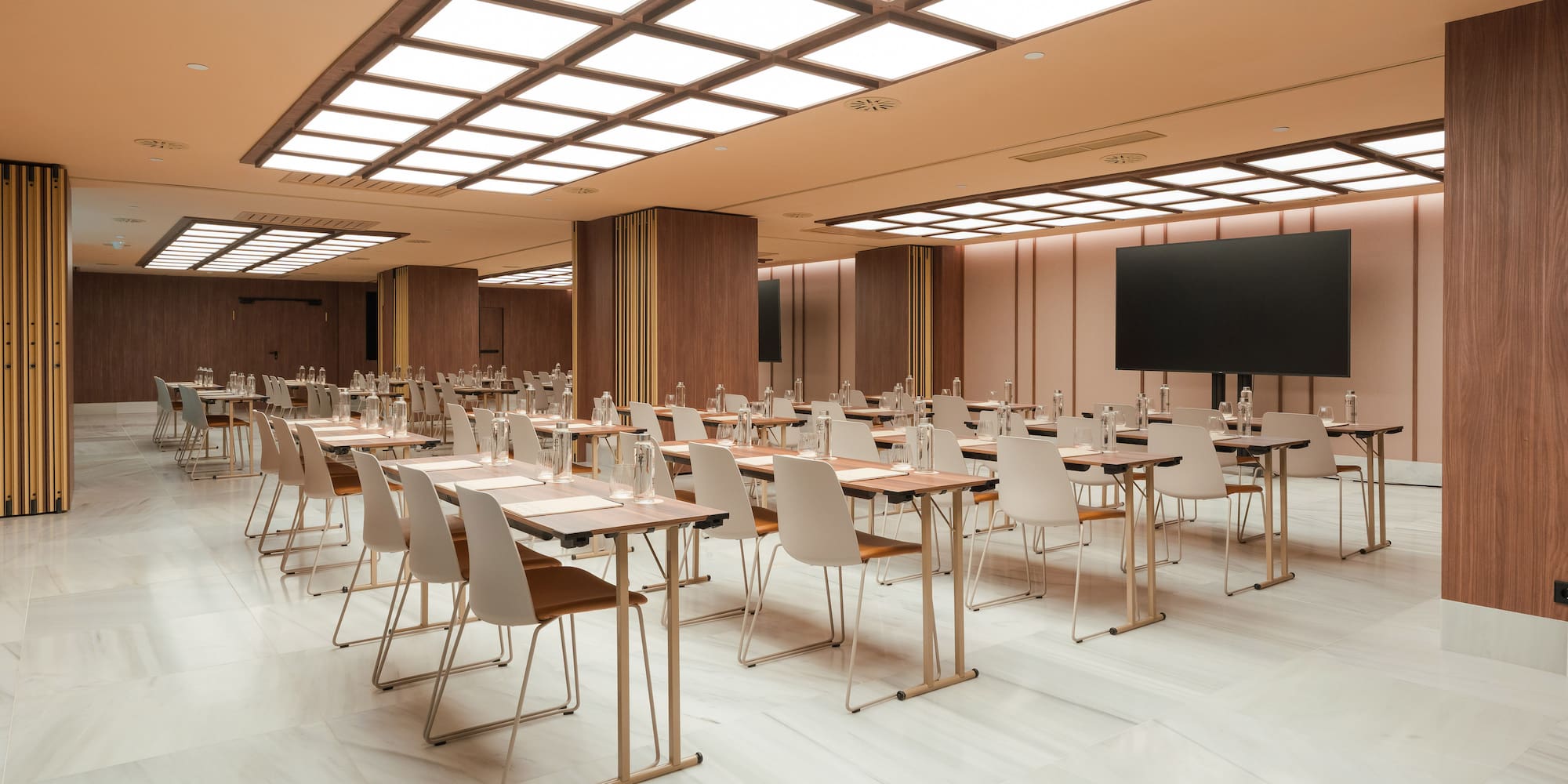 Sleek meeting room with tables, chairs, large screen for presentations.