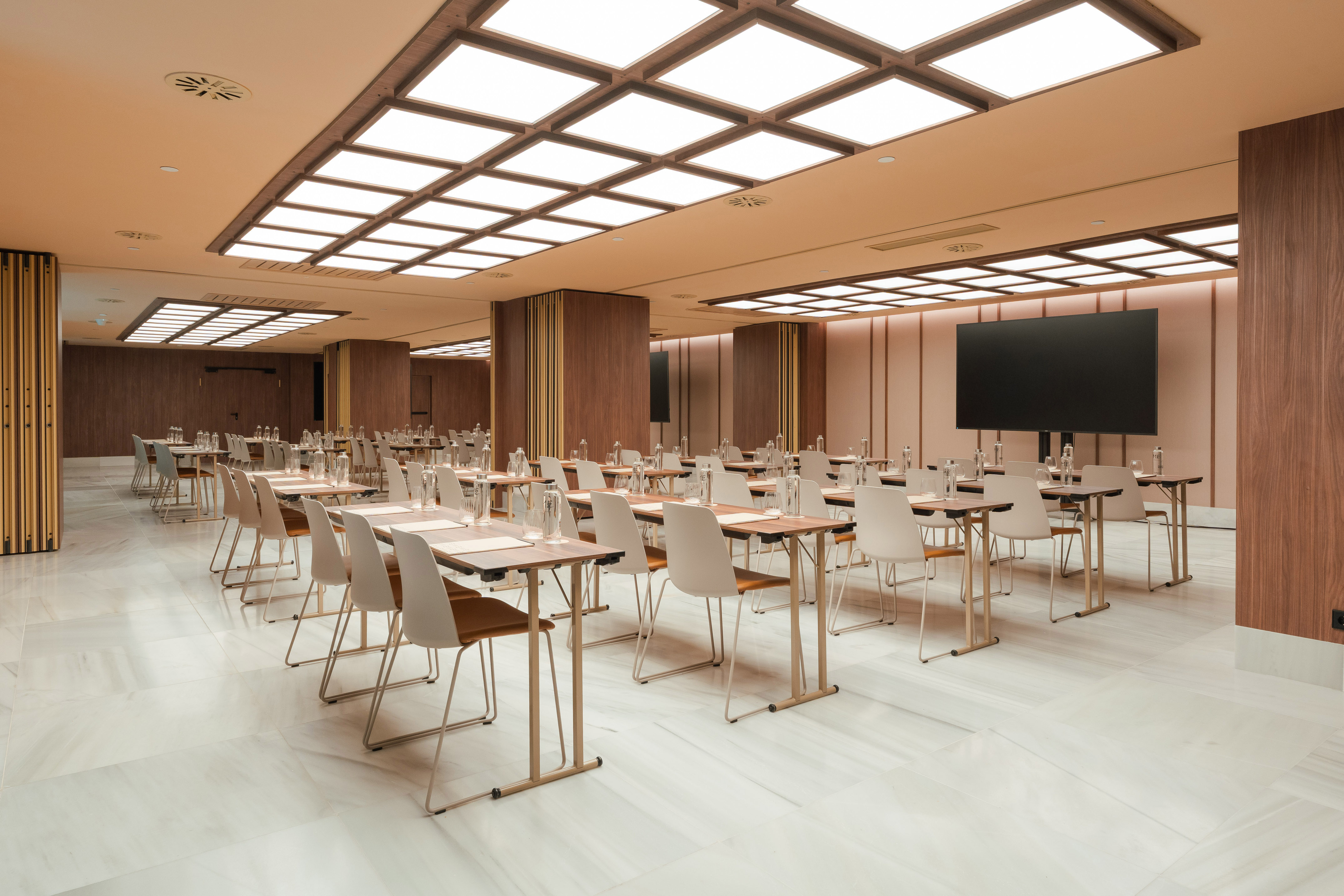 Sleek meeting room with tables, chairs, large screen for presentations.