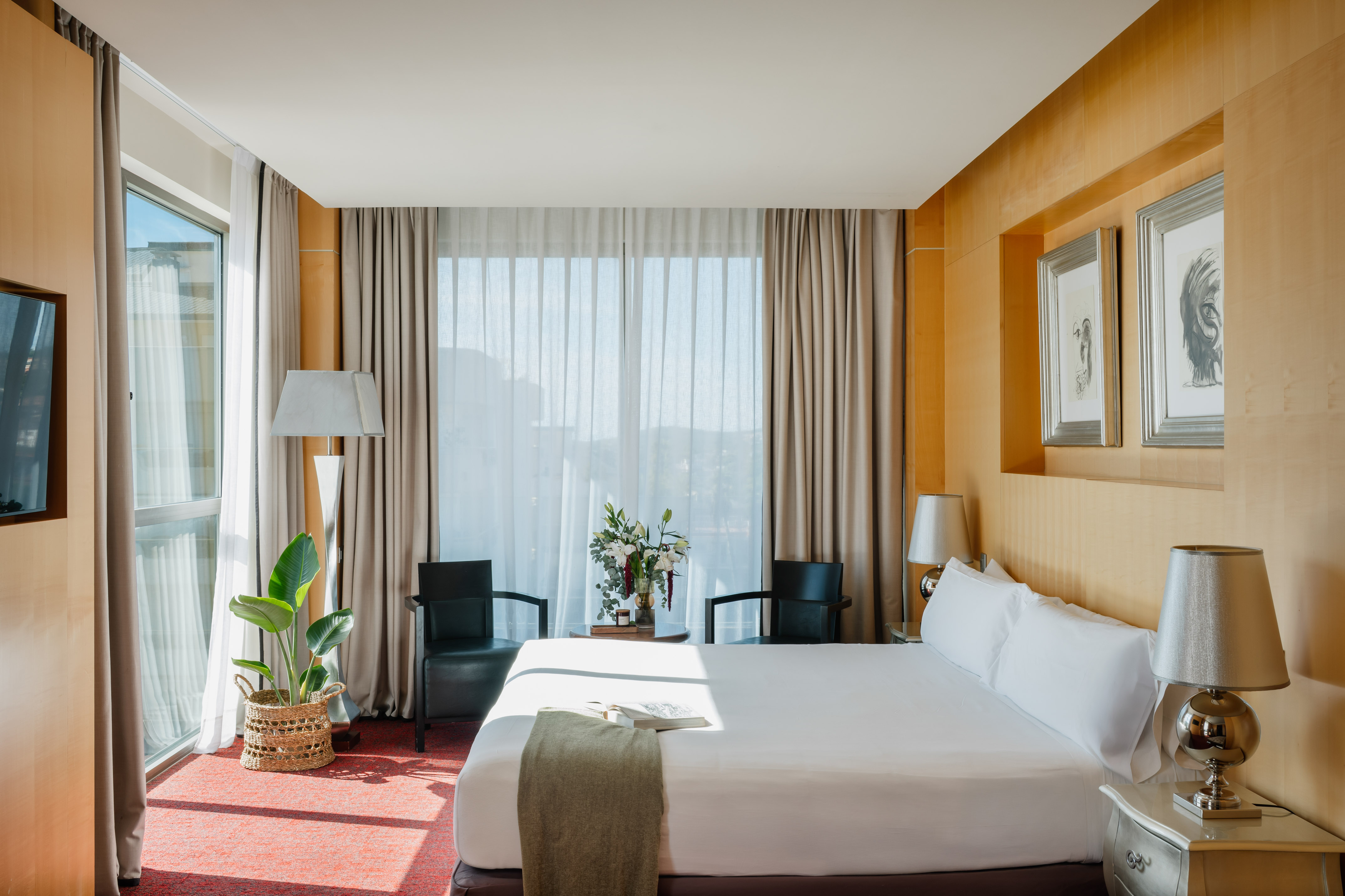 Habitación de hotel moderna, cama grande, ventanal, paneles de madera.