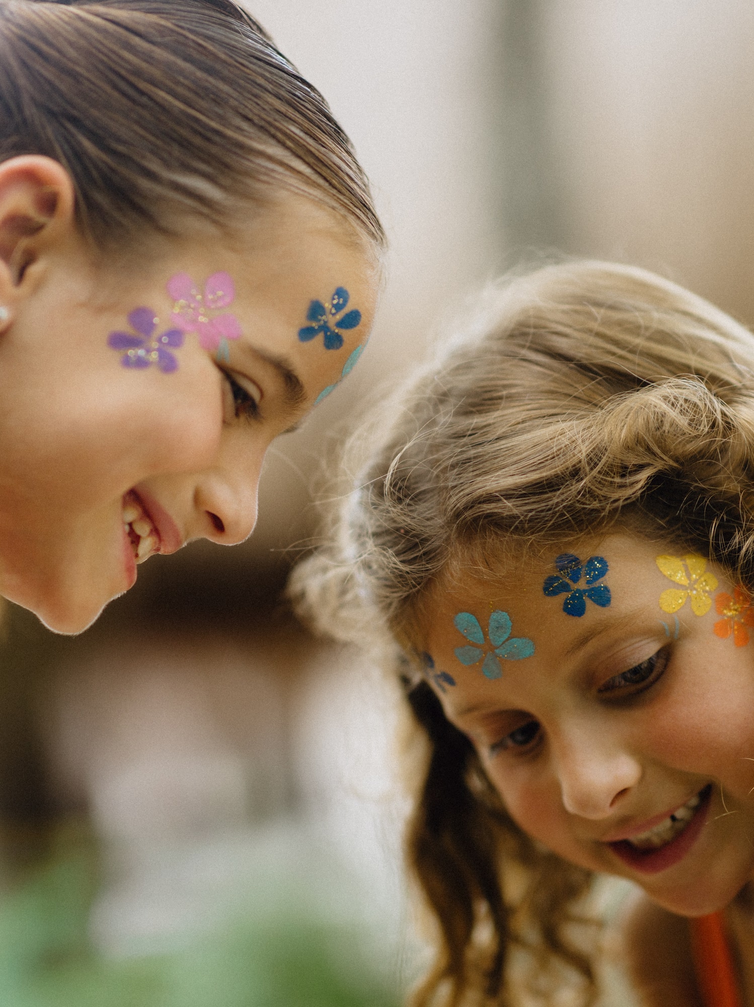 Smiling girls with vibrant glitter flower face paint at a kids party.