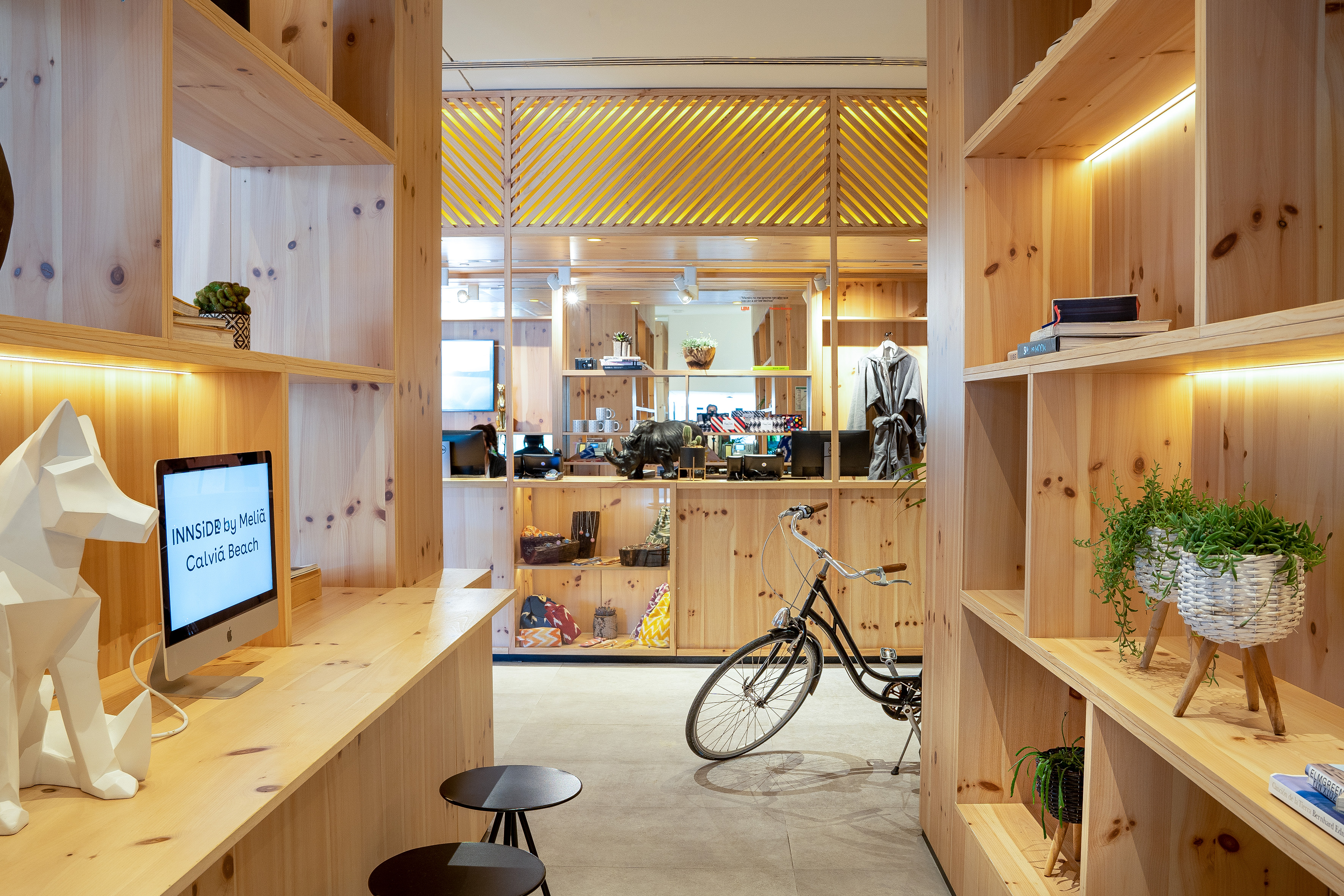 INNSiDE Calviá Beach hotel lobby: modern wood shelving, computer, bicycle.