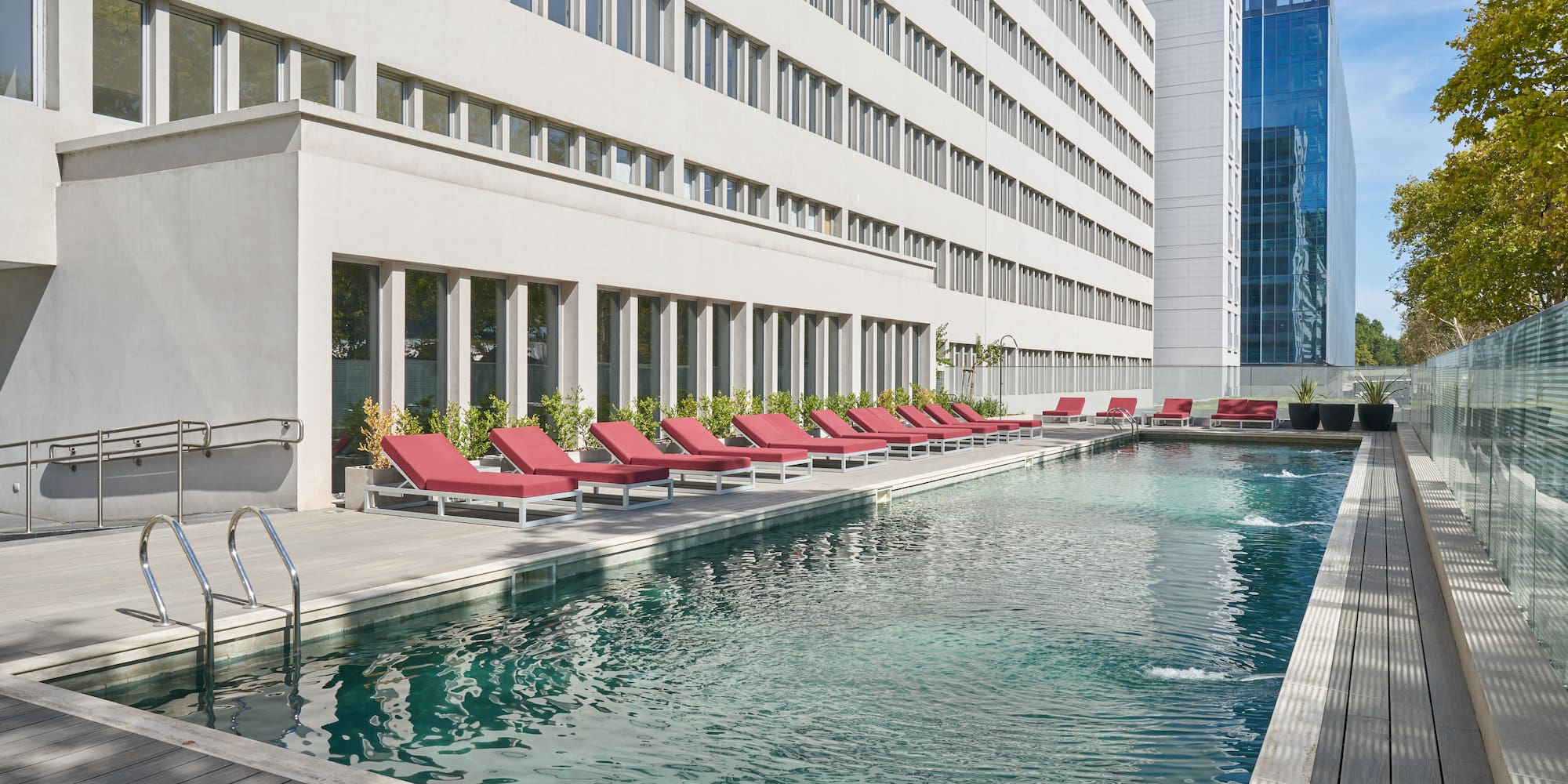 a pool with lounge chairs in front of a building