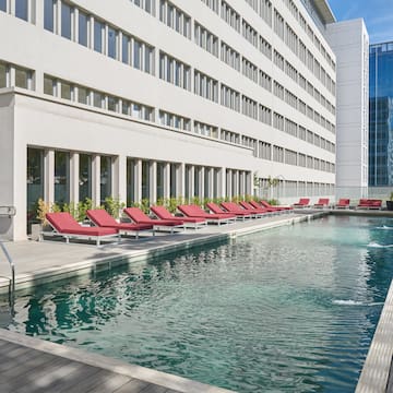 a pool with lounge chairs in front of a building