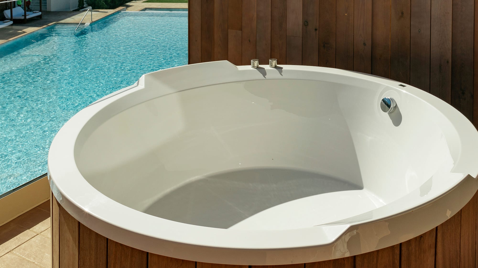 a white round tub next to a pool