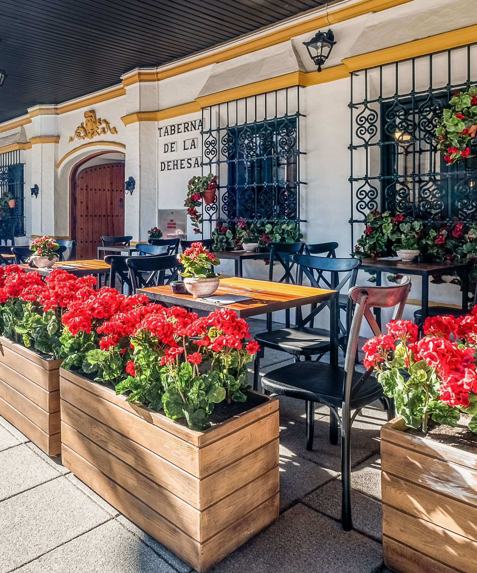a building with tables and chairs and red flowers