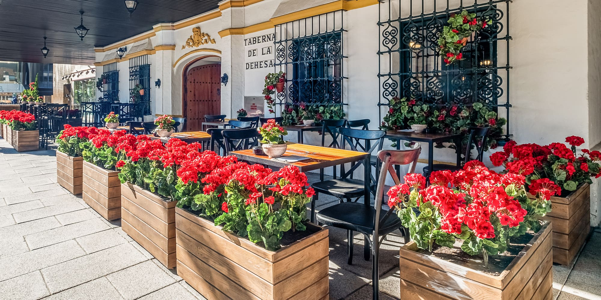a building with tables and chairs and red flowers