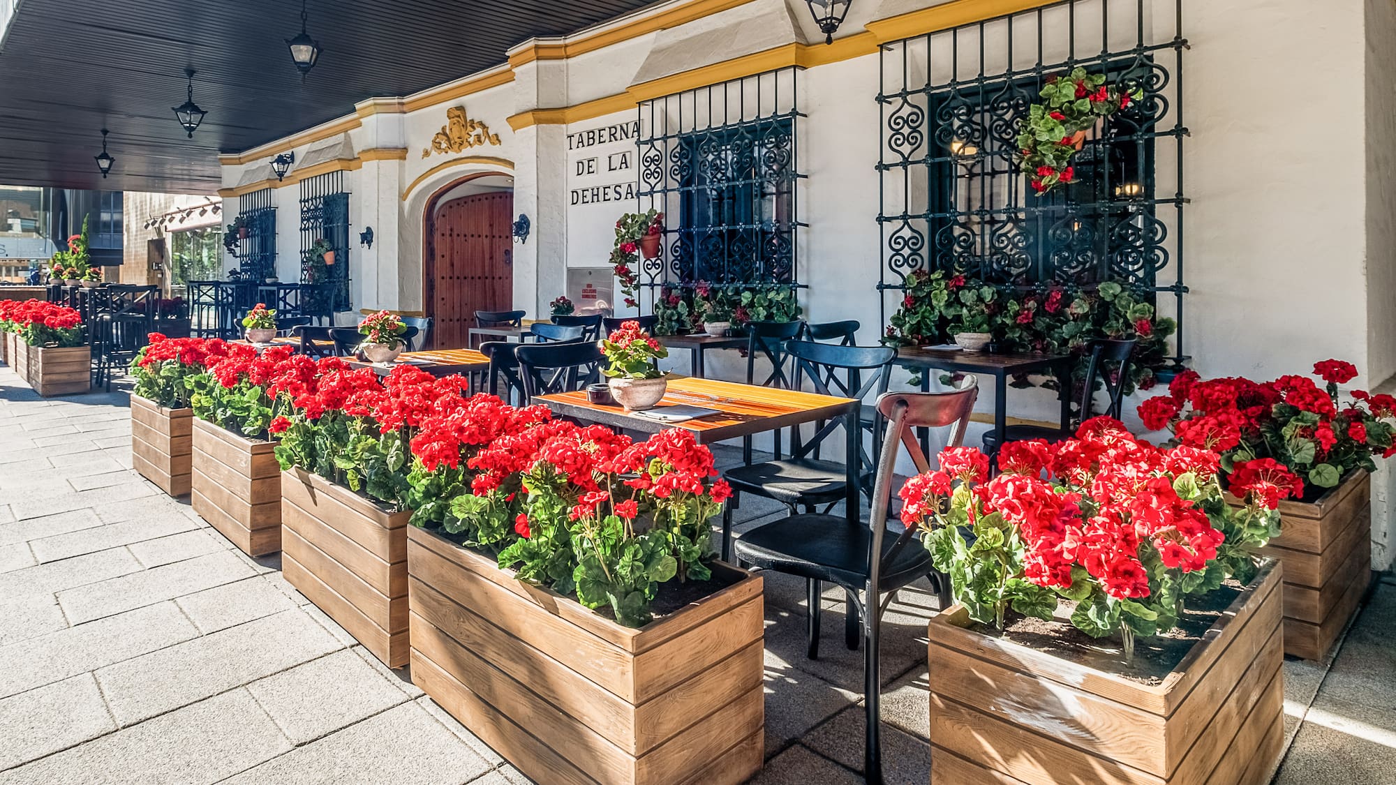 a building with tables and chairs and red flowers