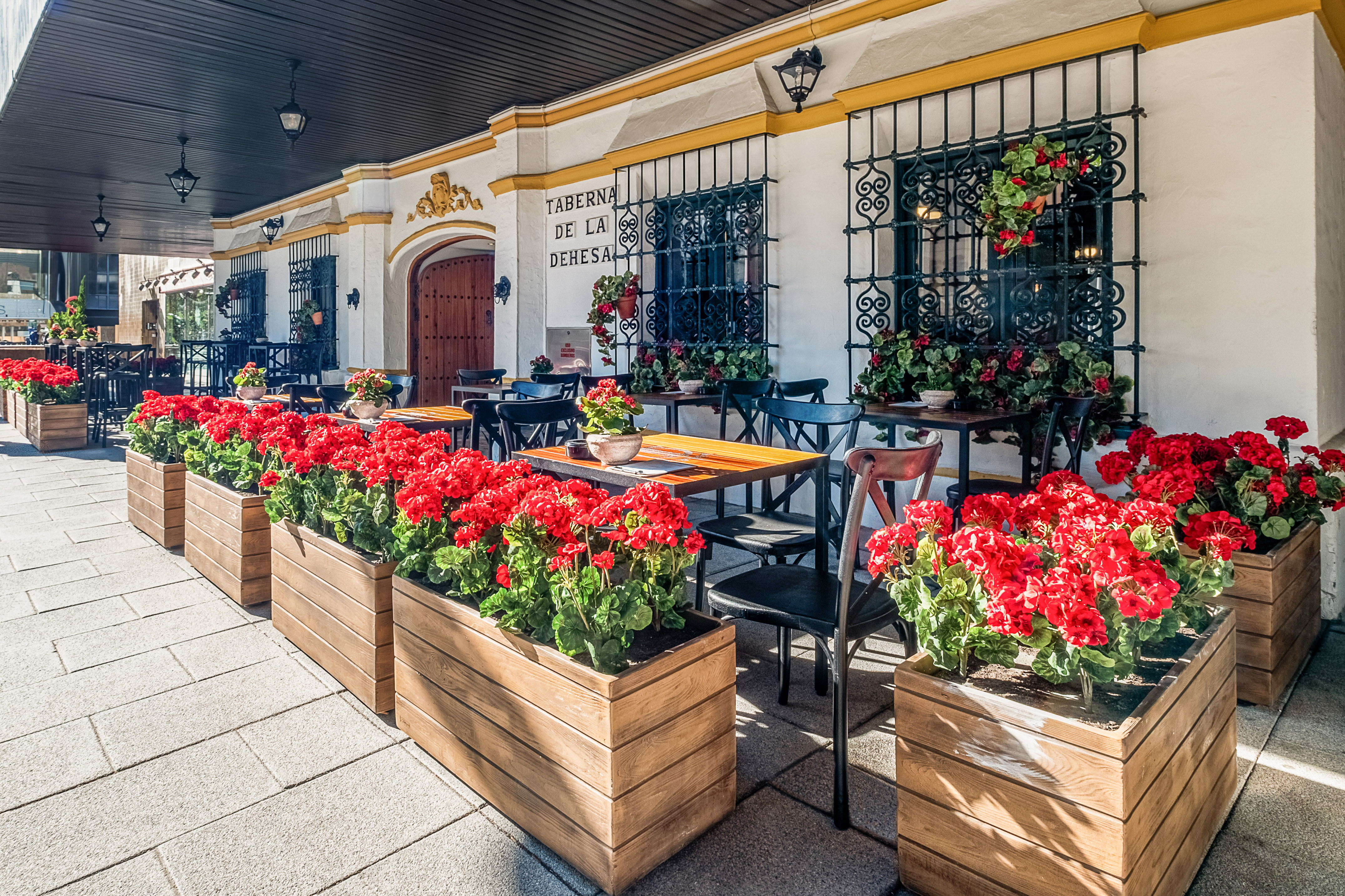 a building with tables and chairs and red flowers
