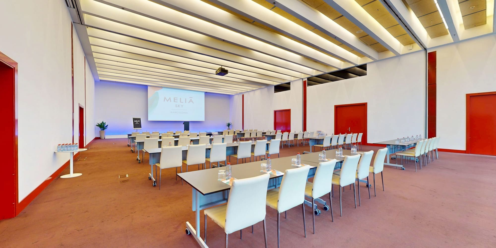 Modern Meliá Sky Barcelona conference room with projector screen, classroom setup.