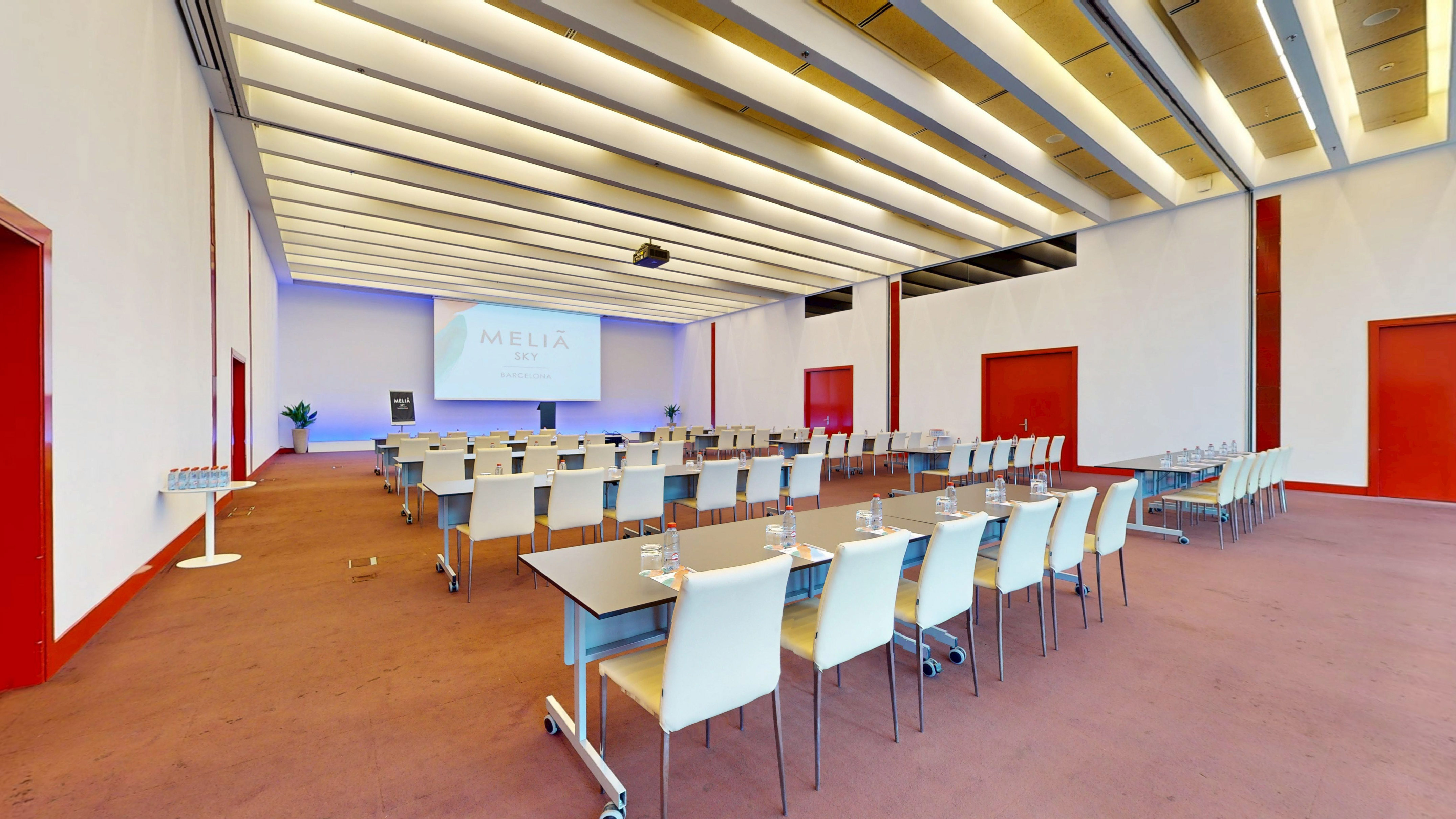 Modern Meliá Sky Barcelona conference room with projector screen, classroom setup.