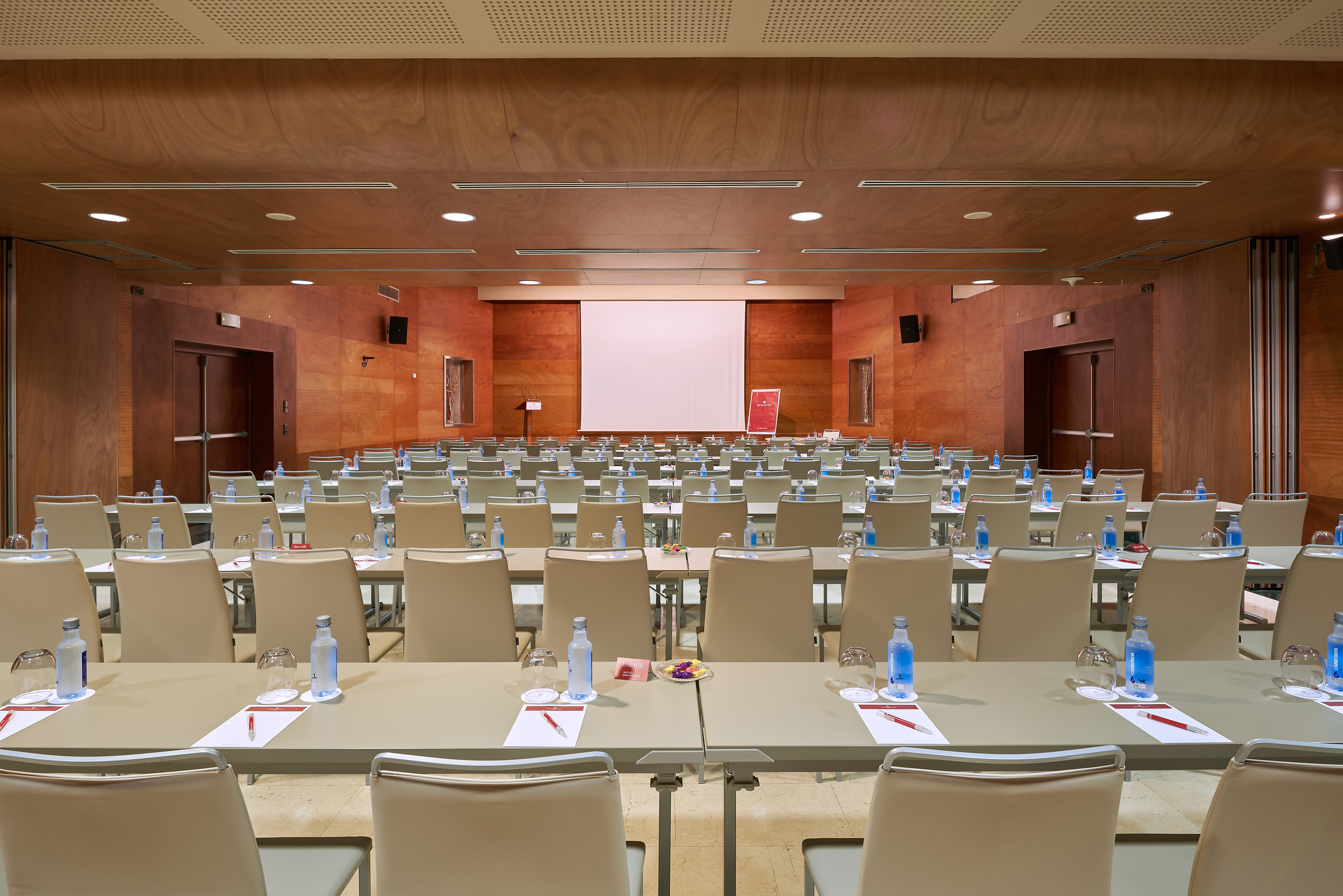 Conference room with tables, chairs, water, and large screen. Ready for meetings. - Principado B - Palacio de Avilés Afiliat Meliá, Avilés